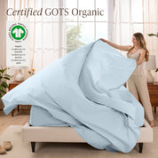 Woman putting bedding on a bed with GOTS Organic certification logo in the corner.