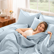 Woman lying in bed under percale sheets with a bright room setting
