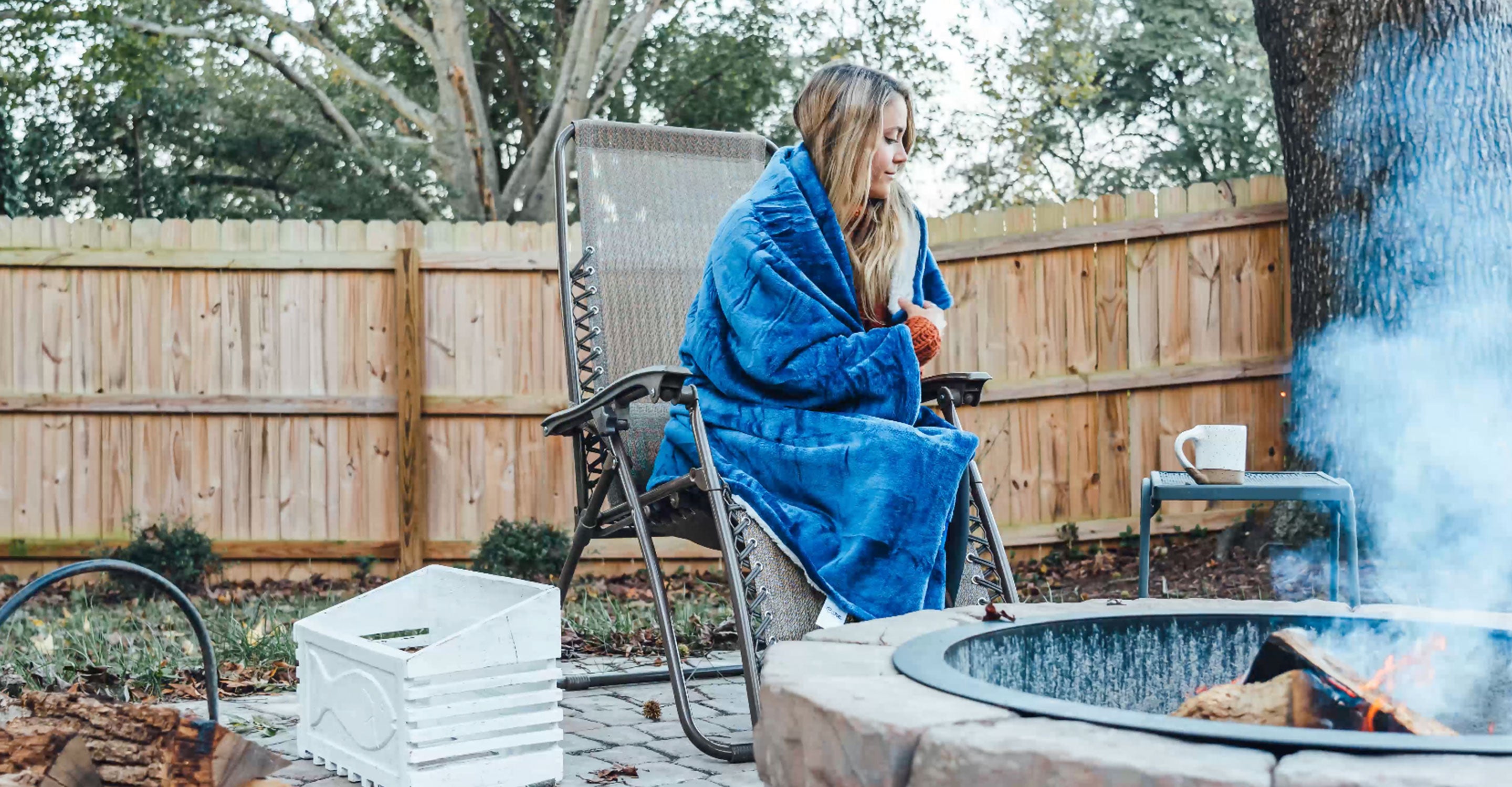 A woman wrapped in a blanket next to a fire