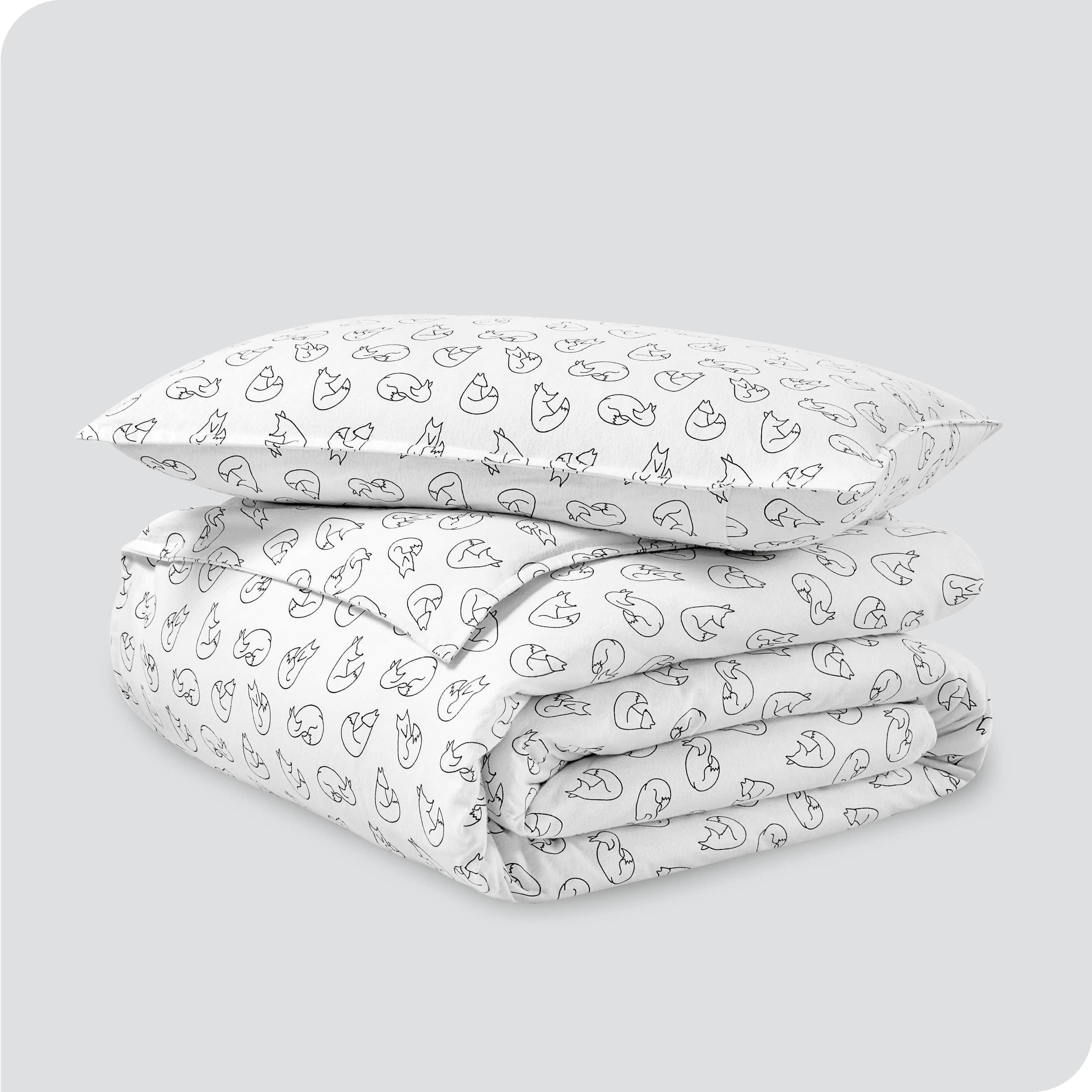 A folded stack of a printed flannel duvet cover with one pillow on top.