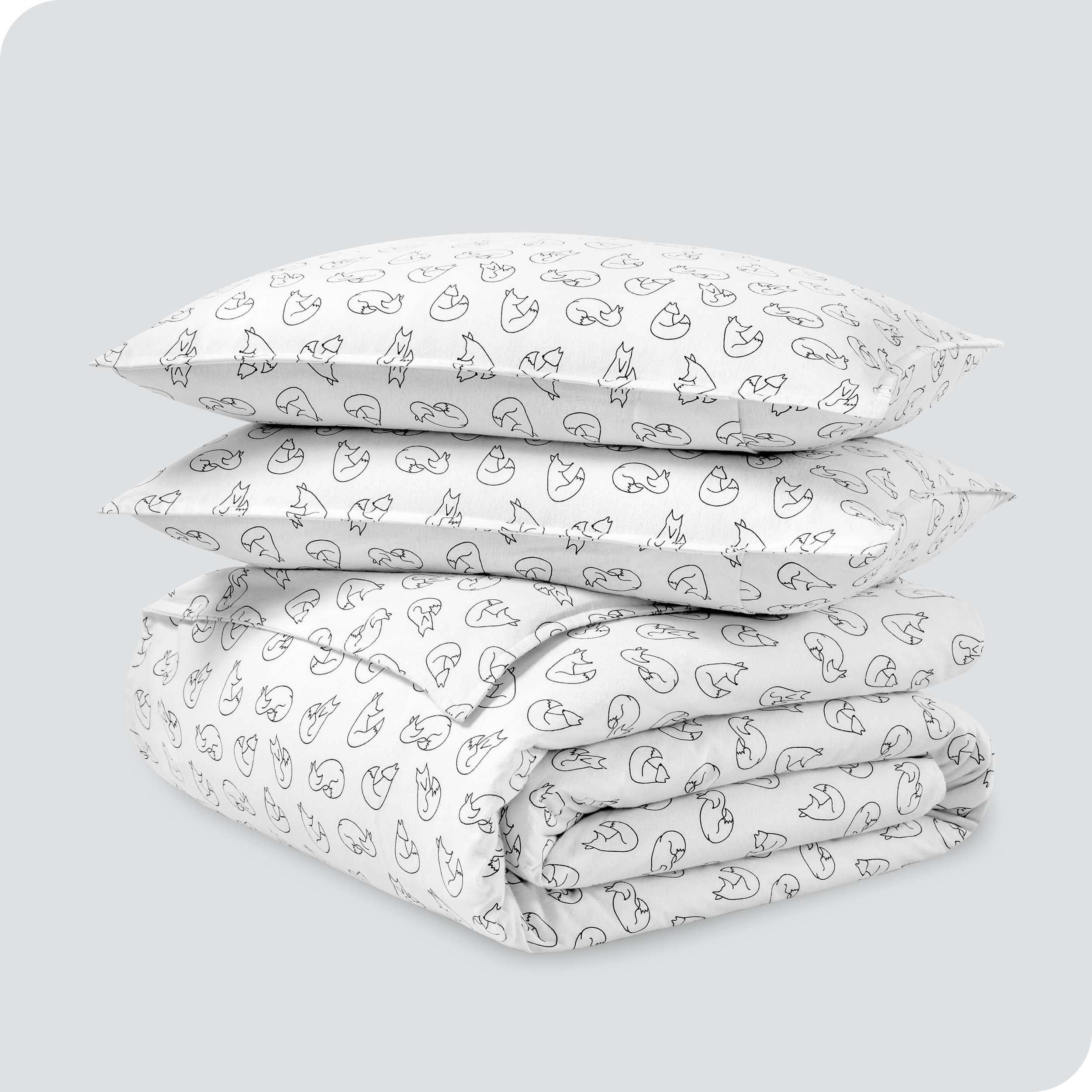 A folded stack of a printed flannel duvet cover with two pillows on top.