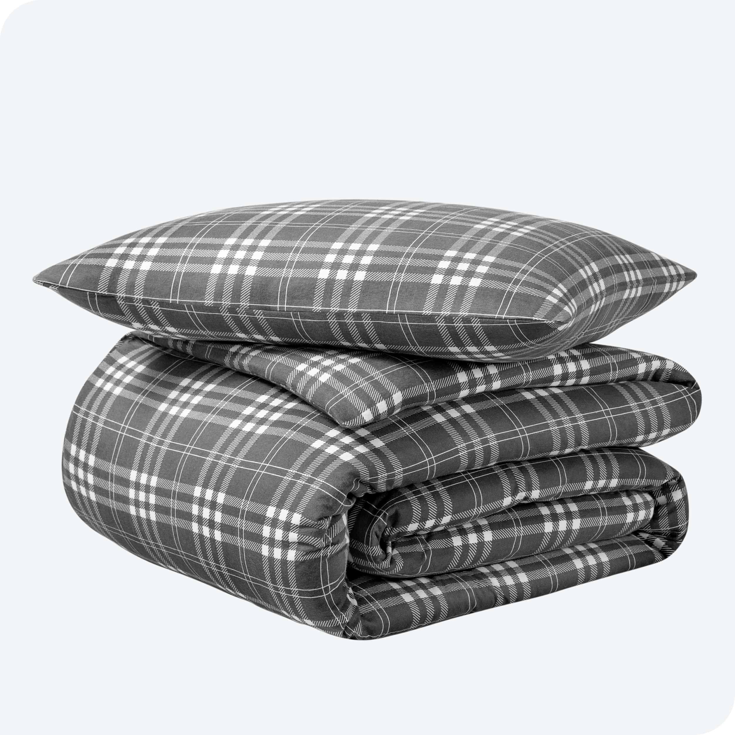 A folded stack of a printed flannel duvet cover with one pillow on top.