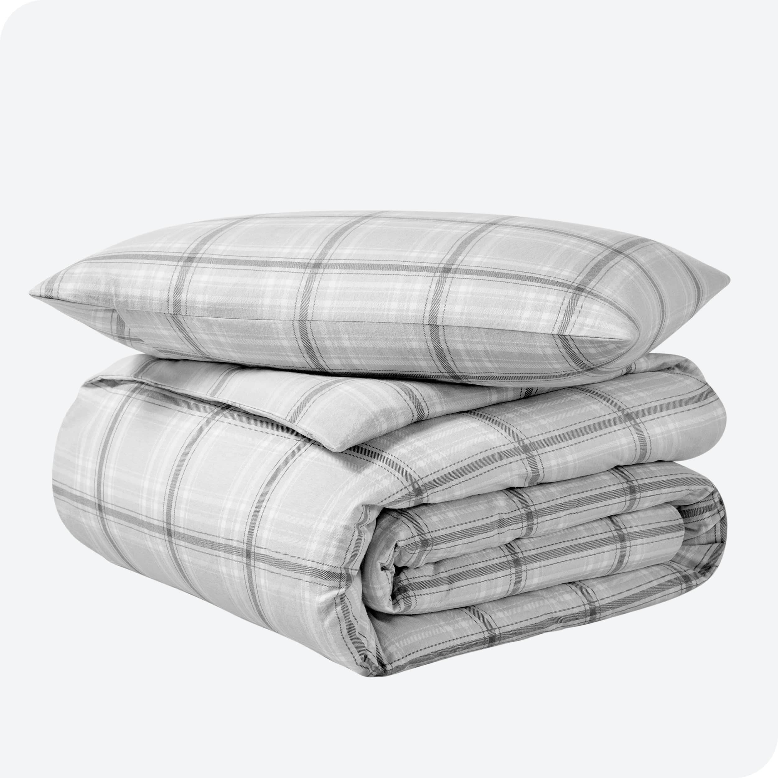 A folded stack of a printed flannel duvet cover with one pillow on top.