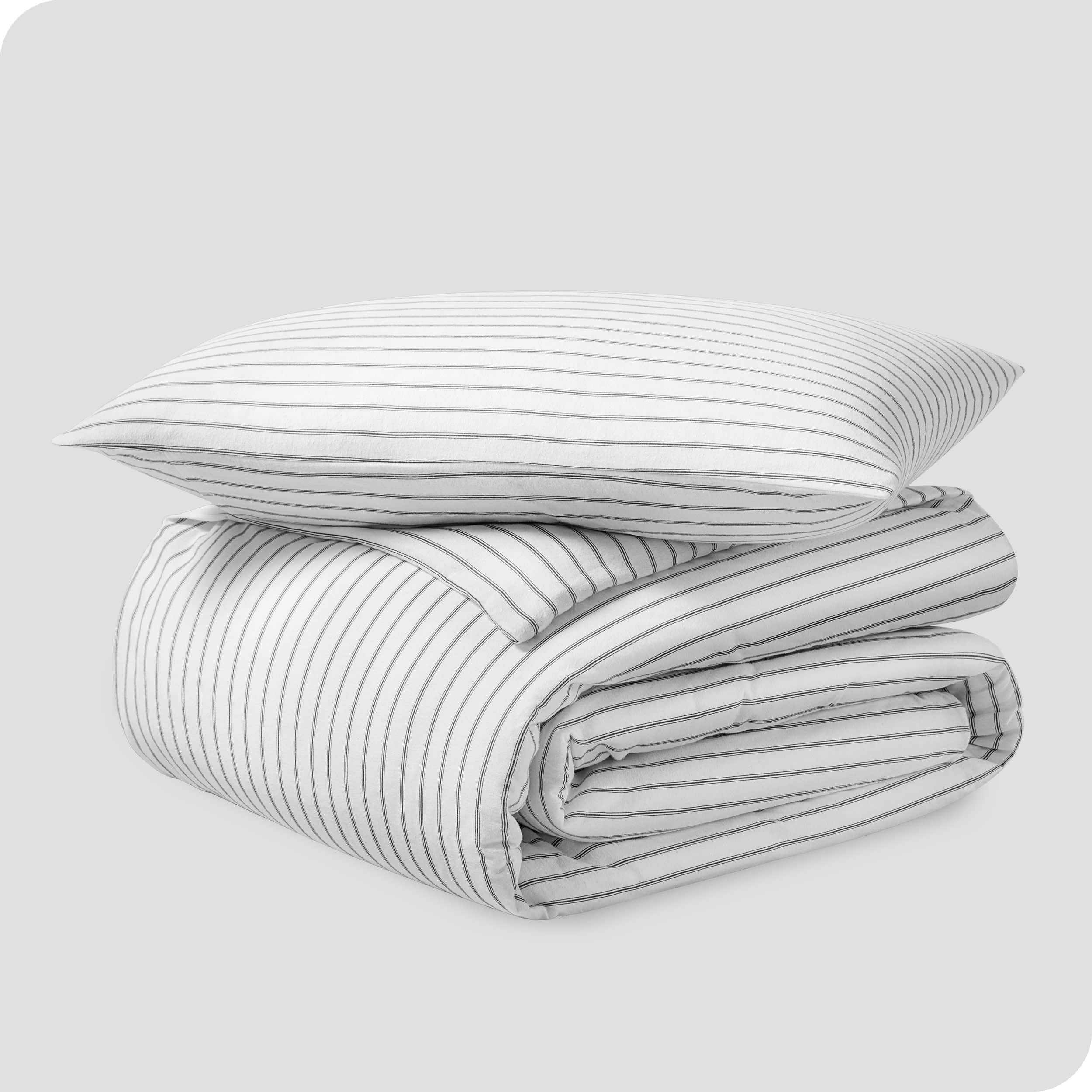 A folded stack of a printed flannel duvet cover with one pillow on top.