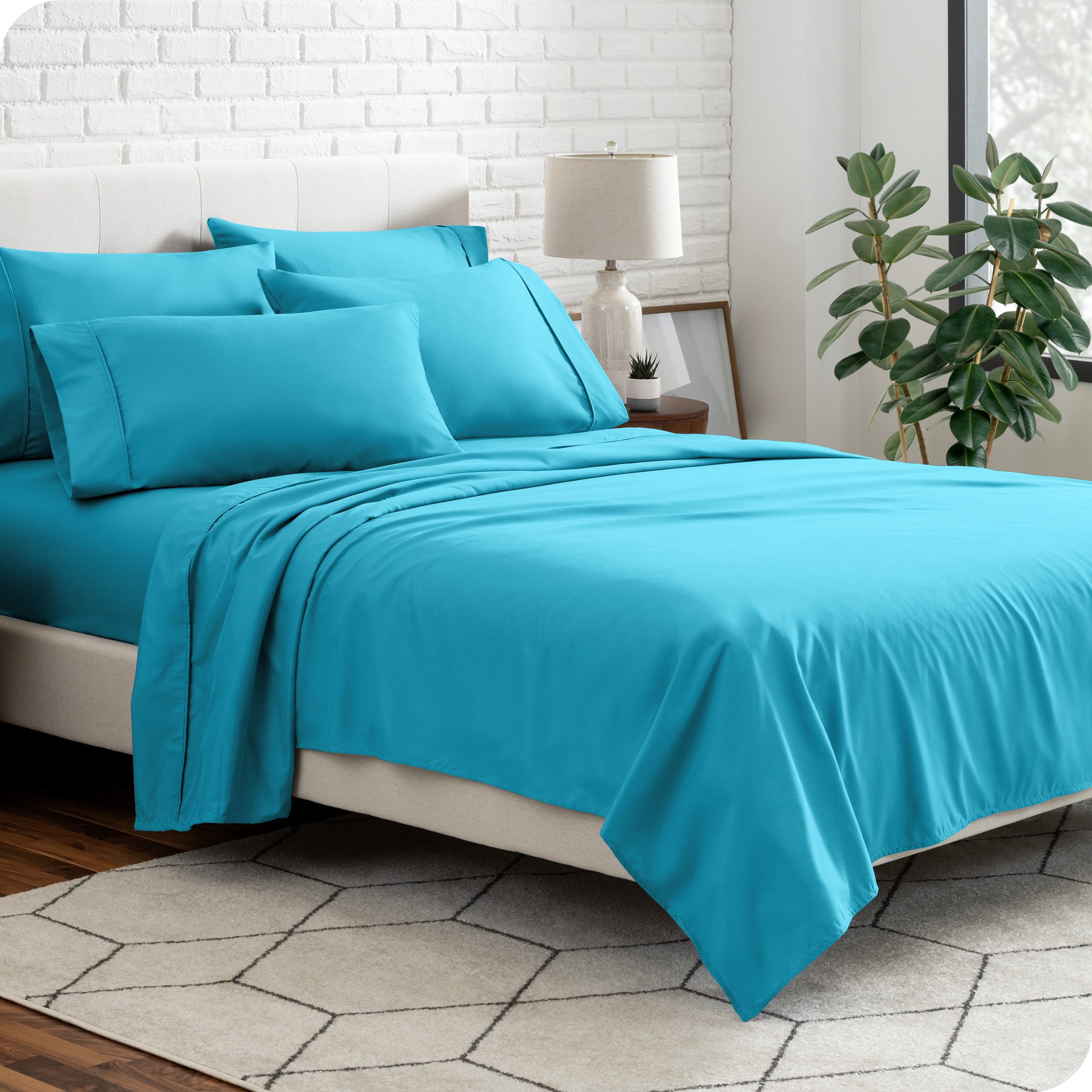 A bedroom setting with a bed made with the microfiber bed sheets and four pillows.