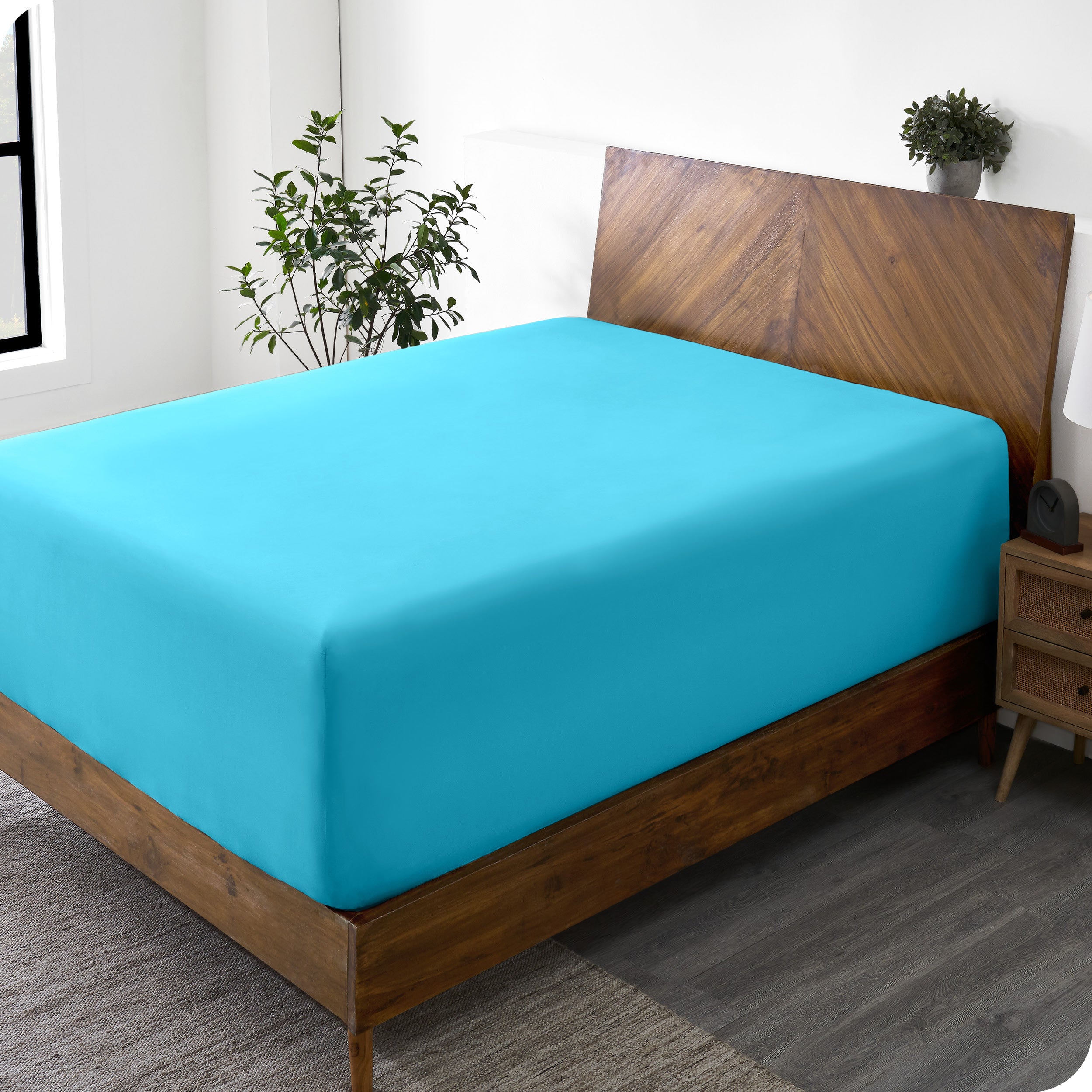 A wide corner view of a modern bed made with a microfiber fitted sheet on the mattress. 