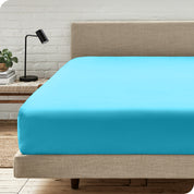 A bed with a microfiber fitted sheet on the mattress. 
