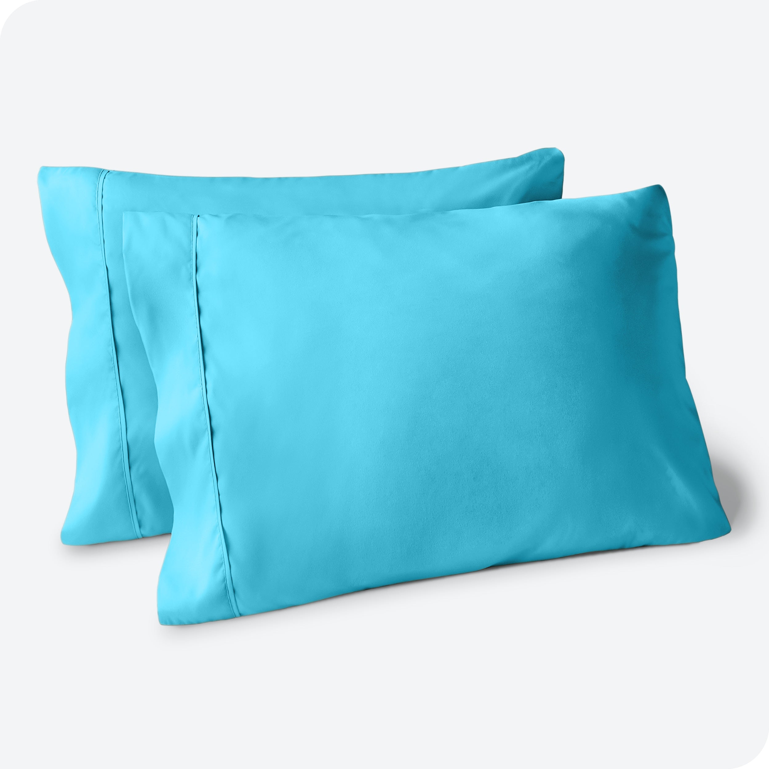 Two pillows on a white background with blue pillowcases on them