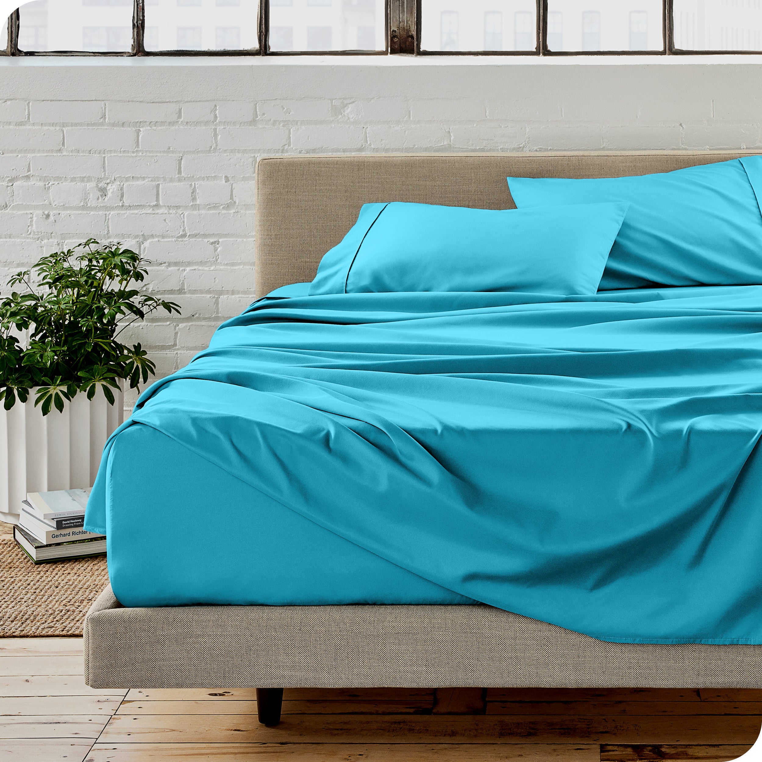 Microfiber sheets on a bed with a brick wall behind it