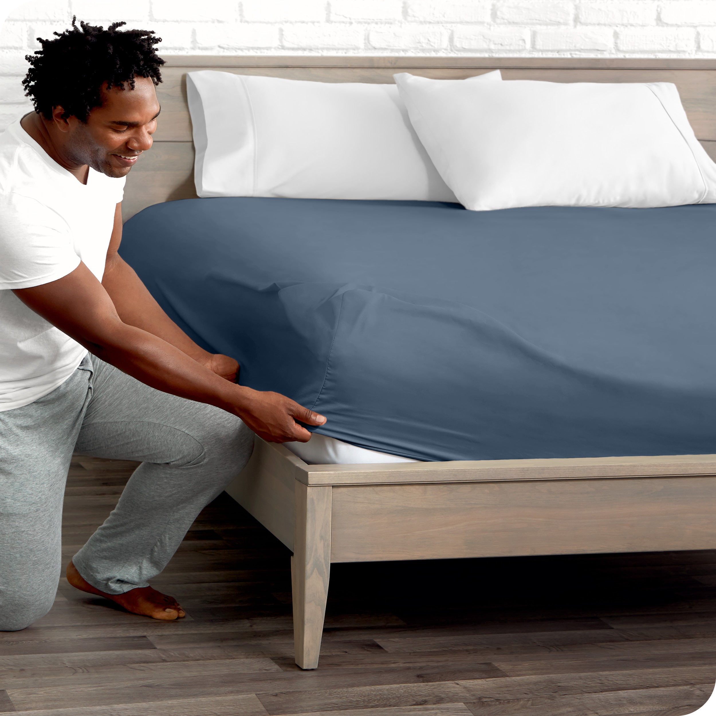 A man putting the microfiber fitted sheet on a mattress. 