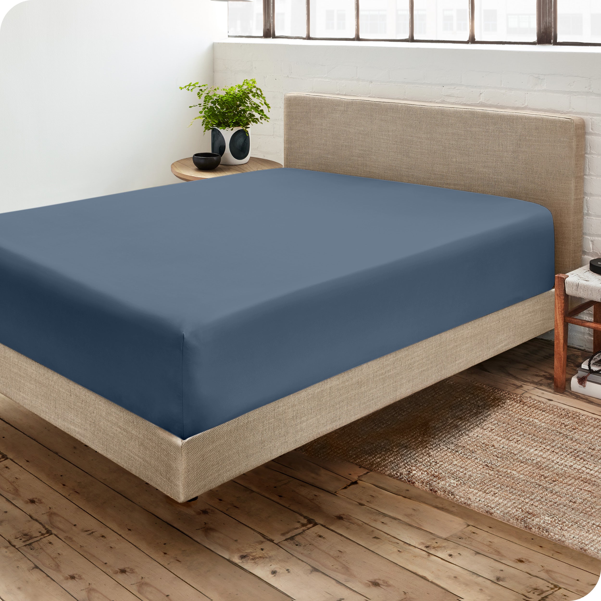 Corner view of a modern bed with a microfiber fitted sheet on the mattress. 