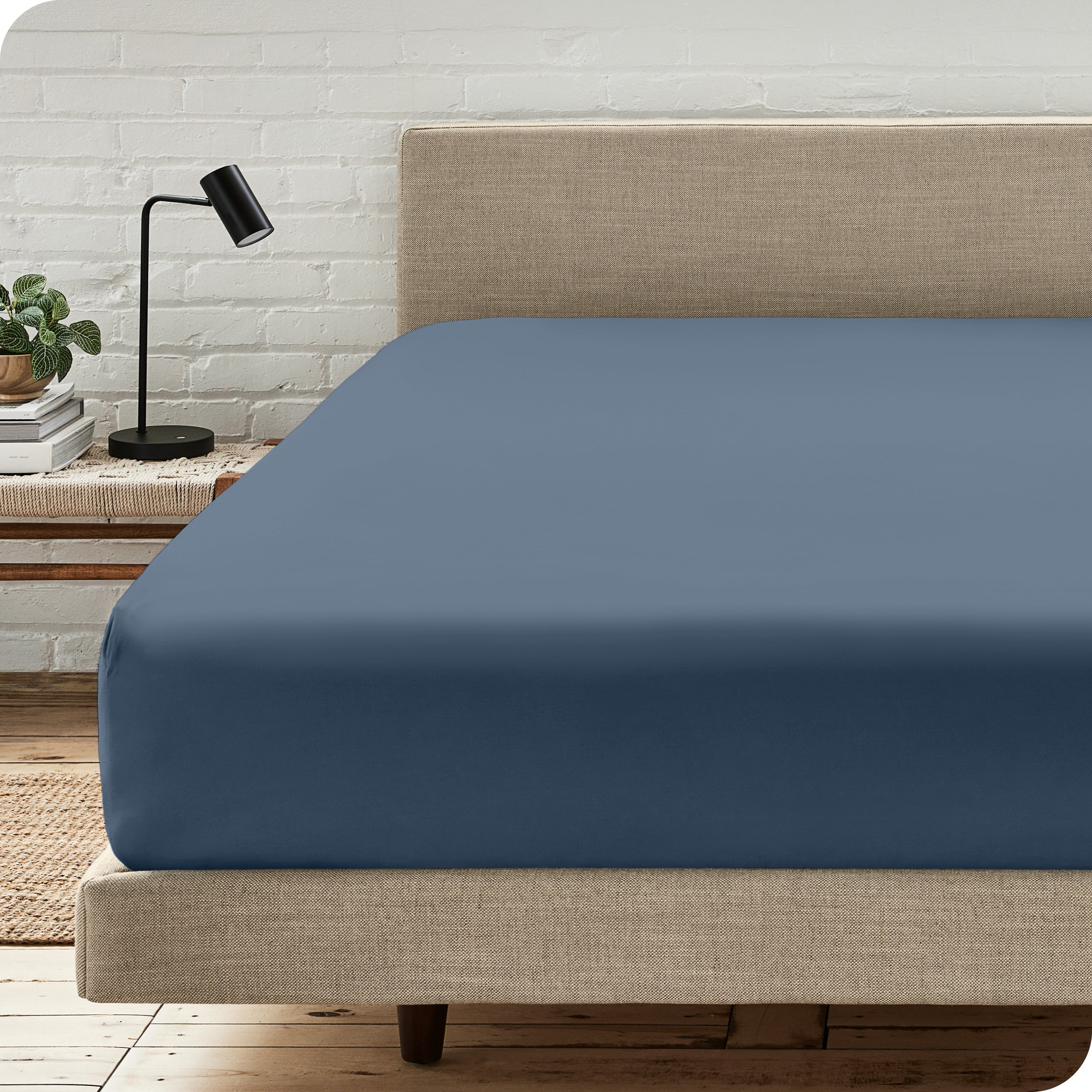 A bed with a microfiber fitted sheet on the mattress. 