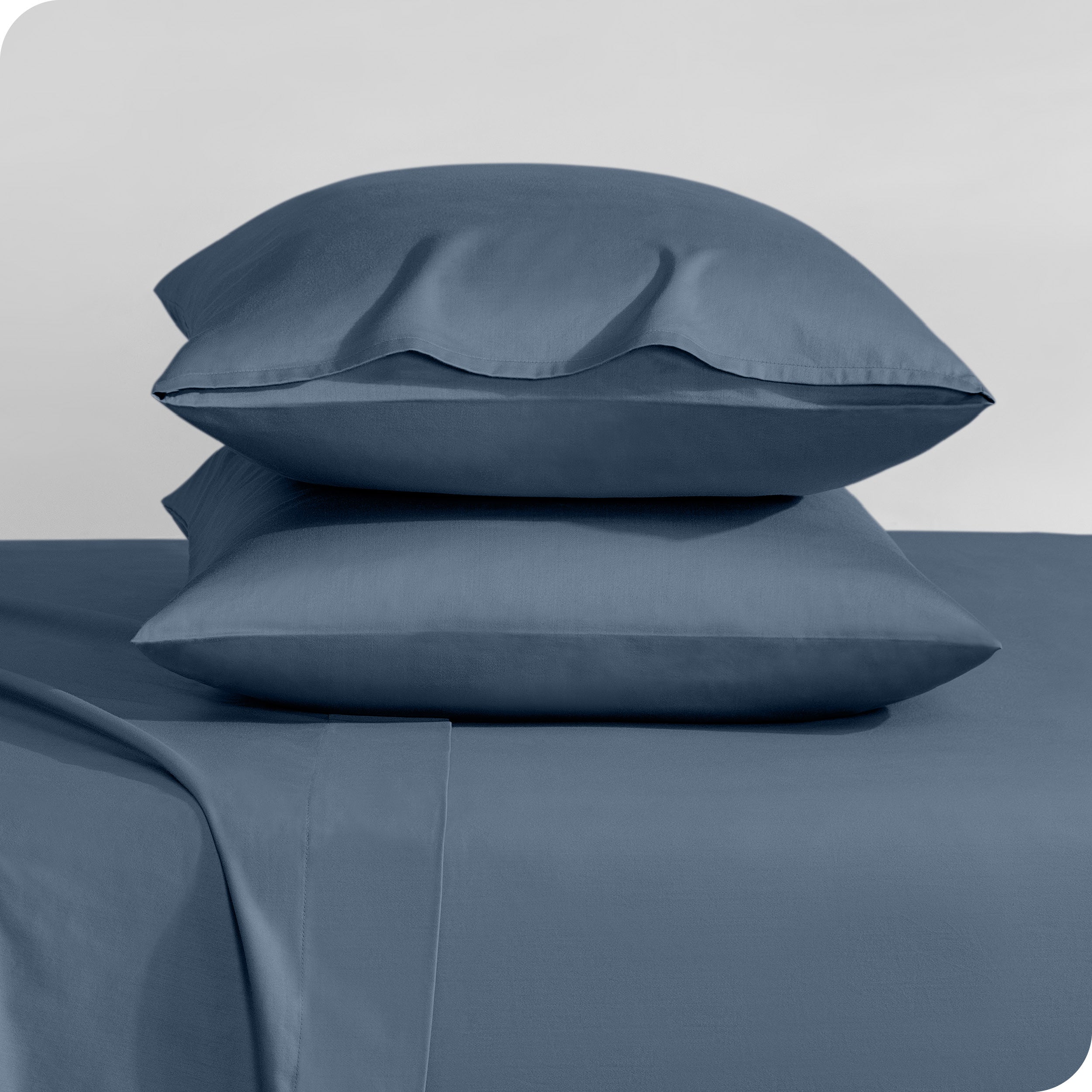Two sateen pillowcases stacked on a bed