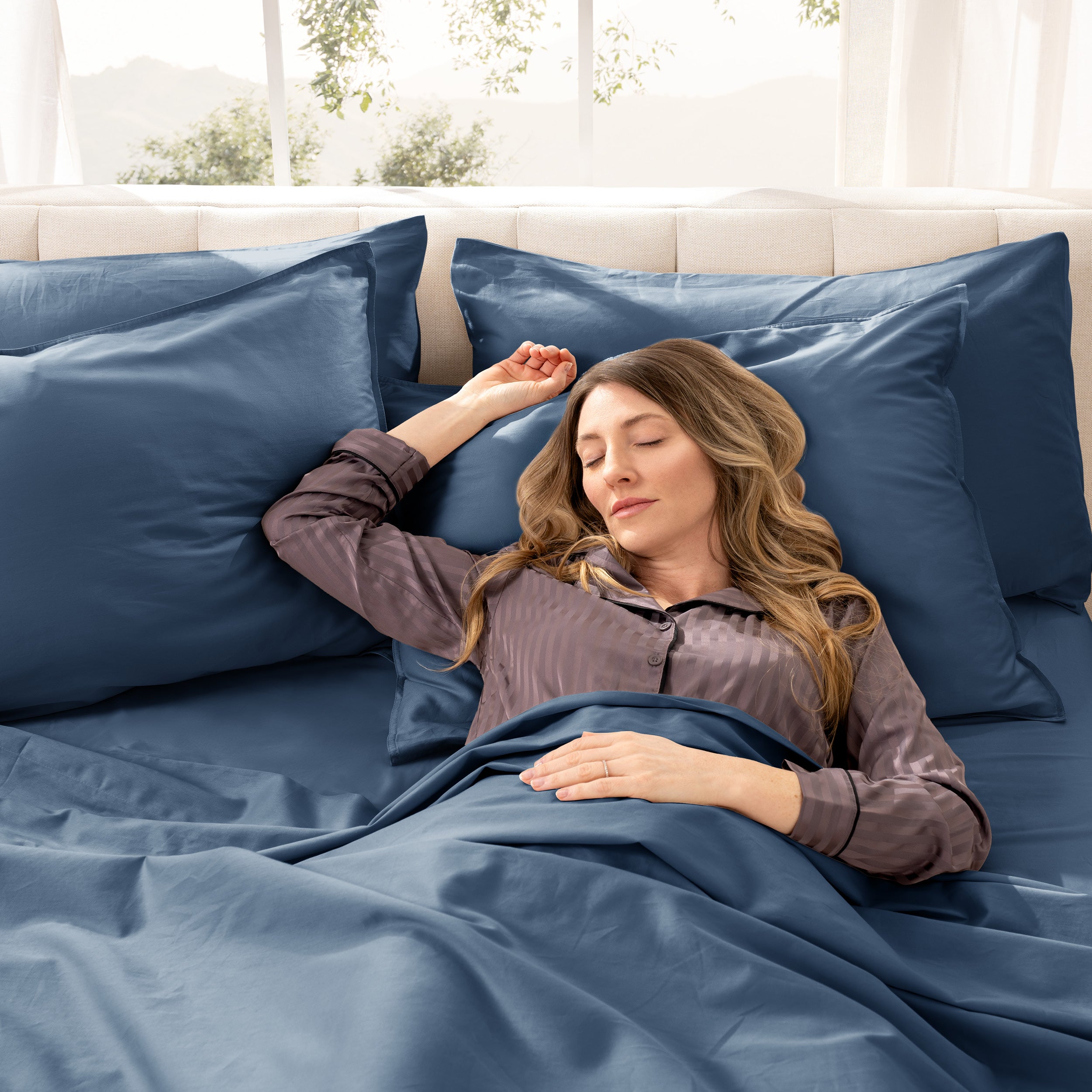 A woman sleeping on a bed made with organic cotton sateen sheets and pillowcases