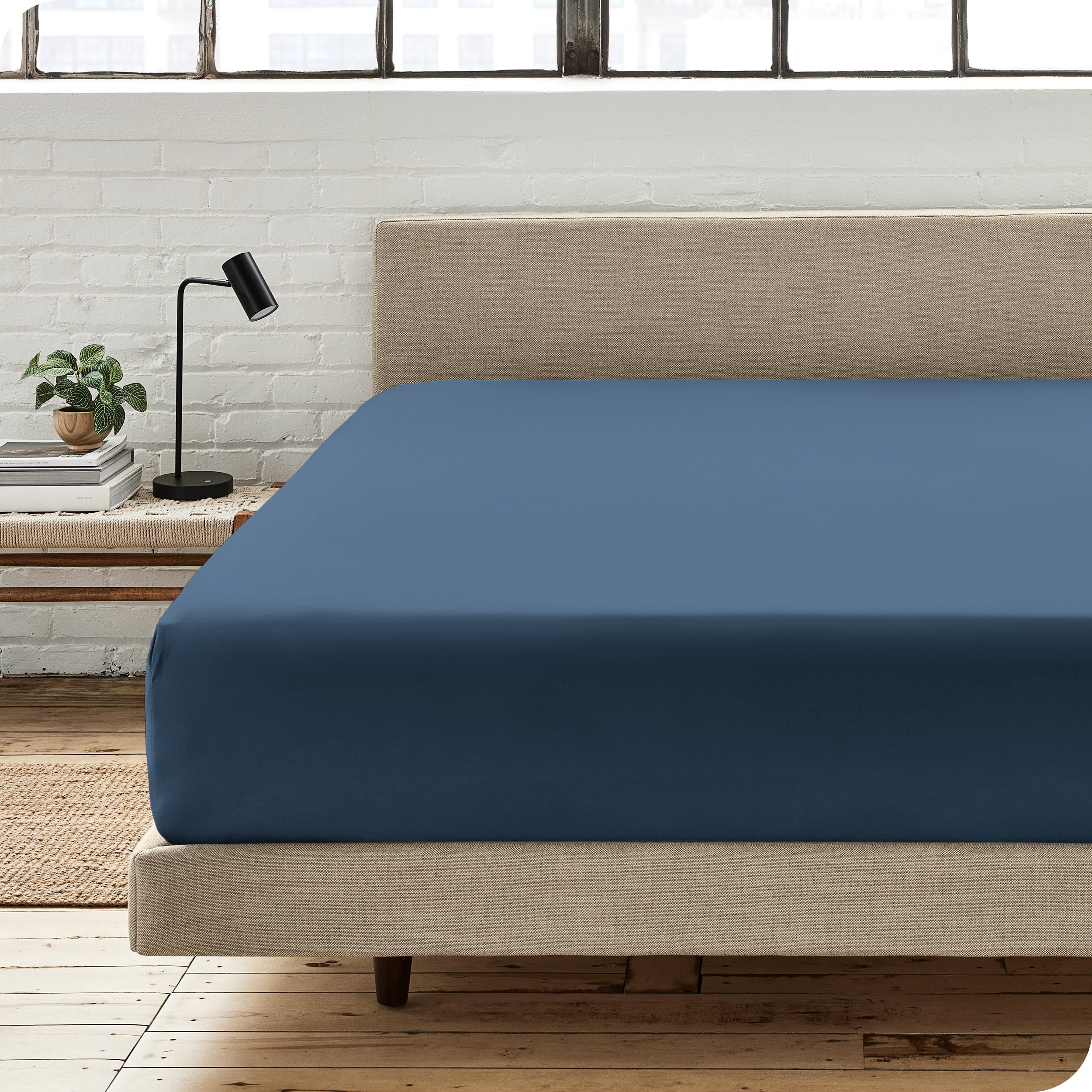 A percale fitted sheet on a bed with table next to it