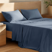 Organic cotton percale sheet set on a bed, with a flat sheet, fitted sheet, and two pillowcases displayed.