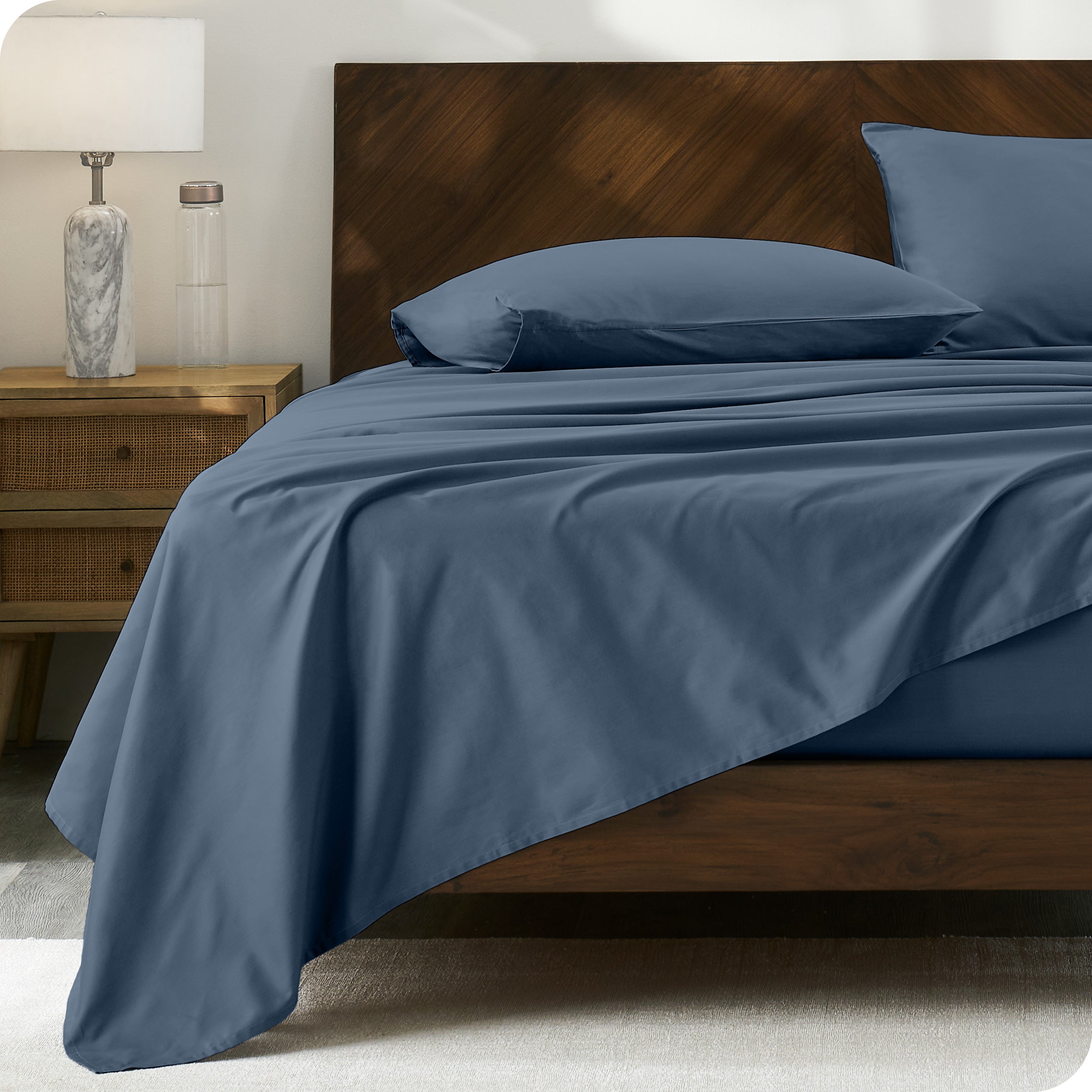 Percale sheet set on a bed with a wooden headboard