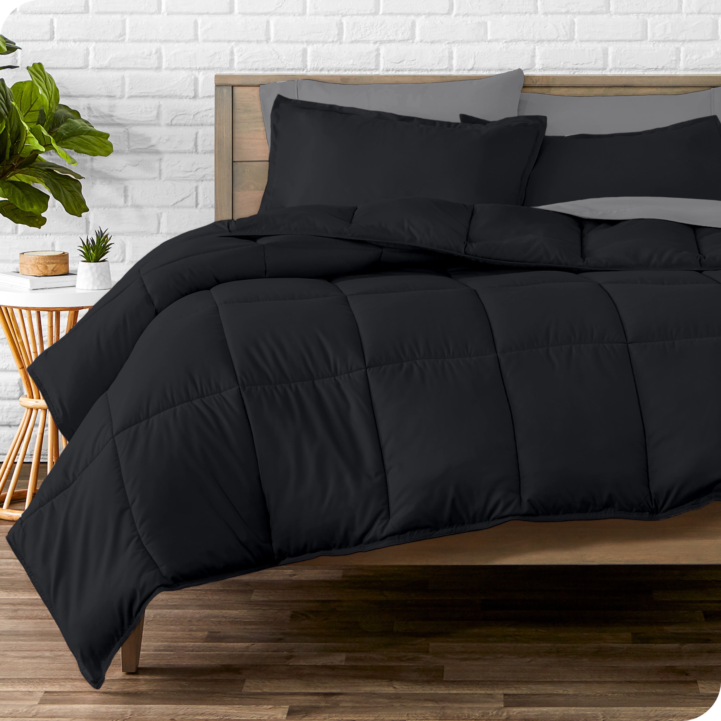 A wooden bed frame with sheets, pillow shams and a comforter on the bed