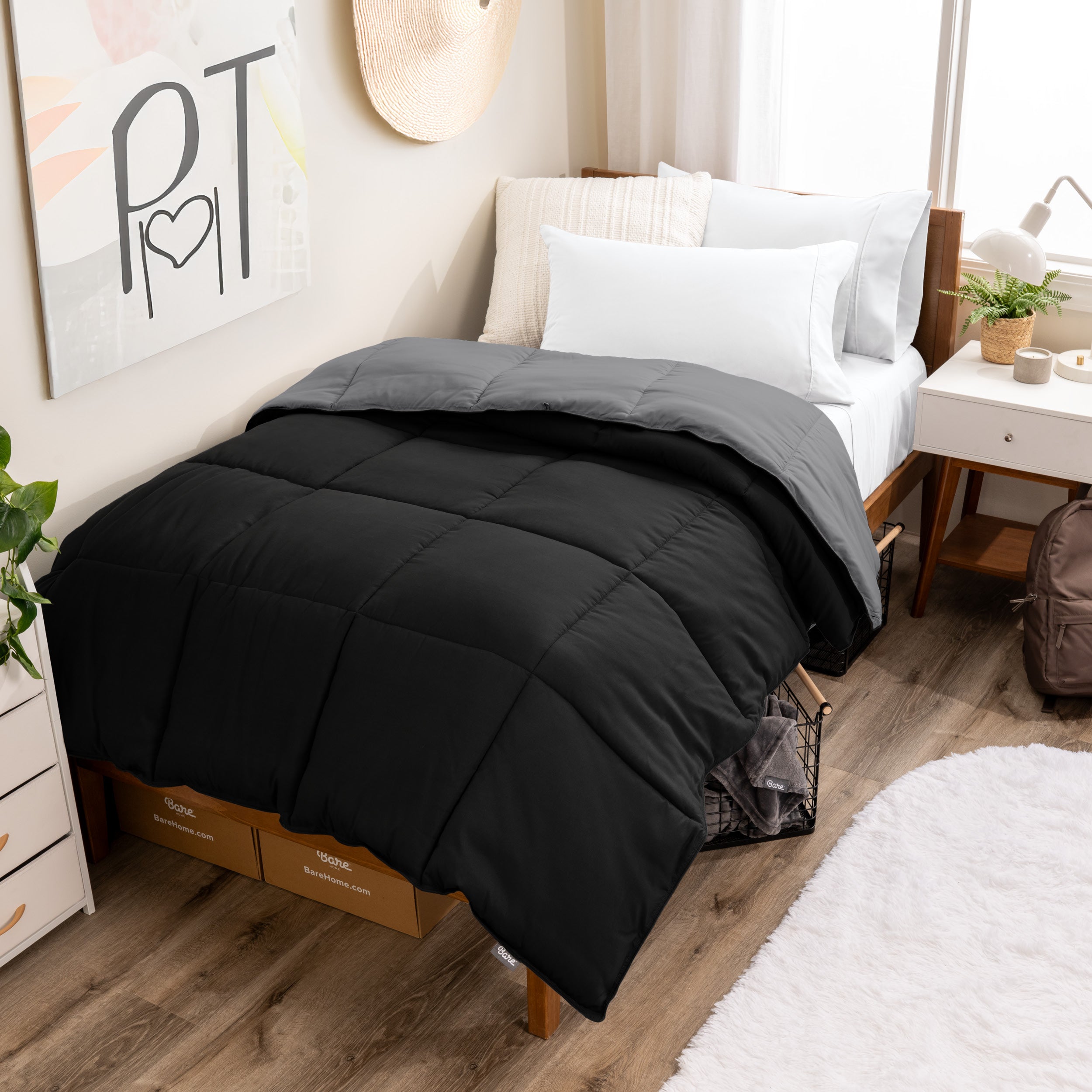 Wooden bed frame with a reversible comforter on the bed. The comforter is folded back over showing the two different colors.