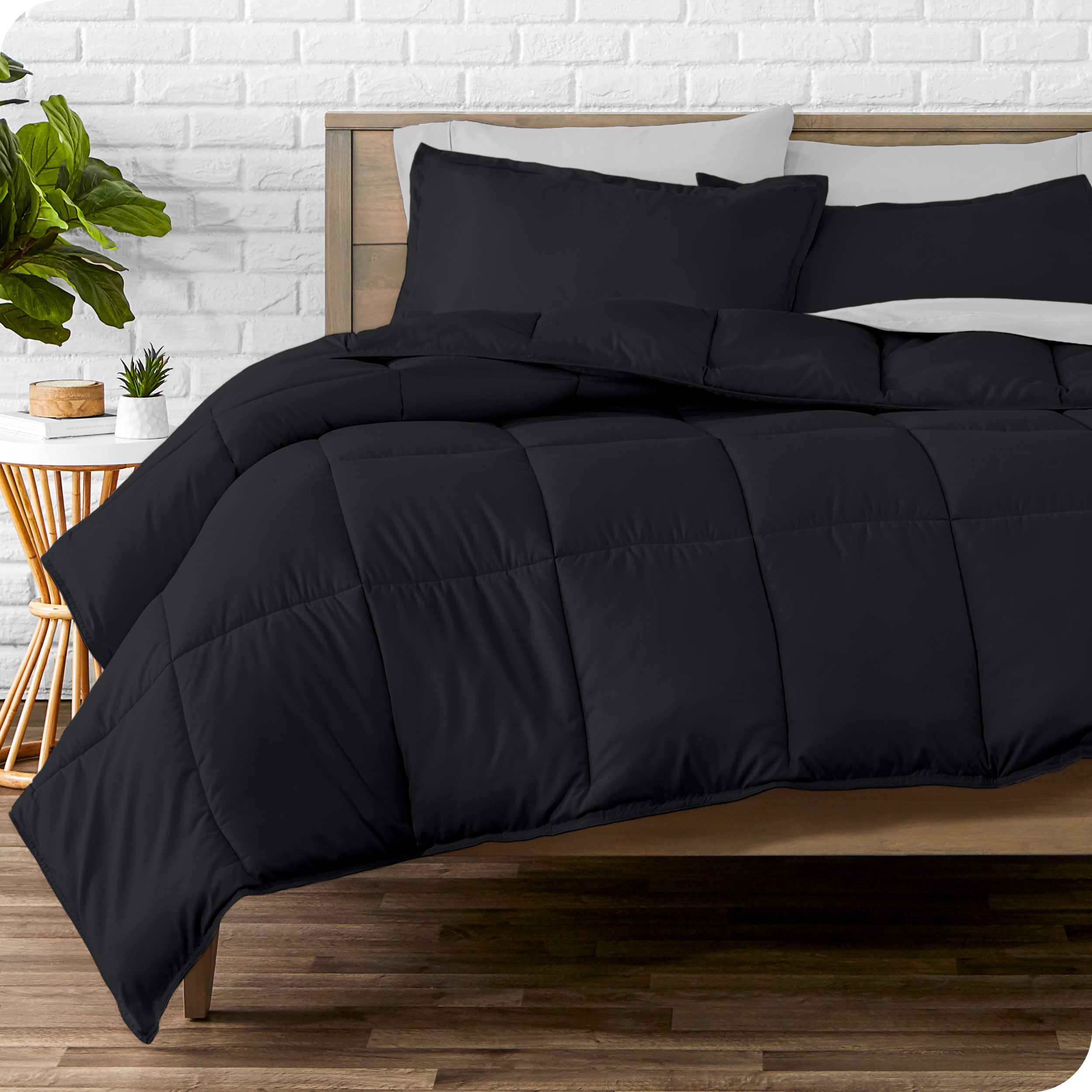 A wooden bed frame with sheets, pillow shams and a comforter on the bed