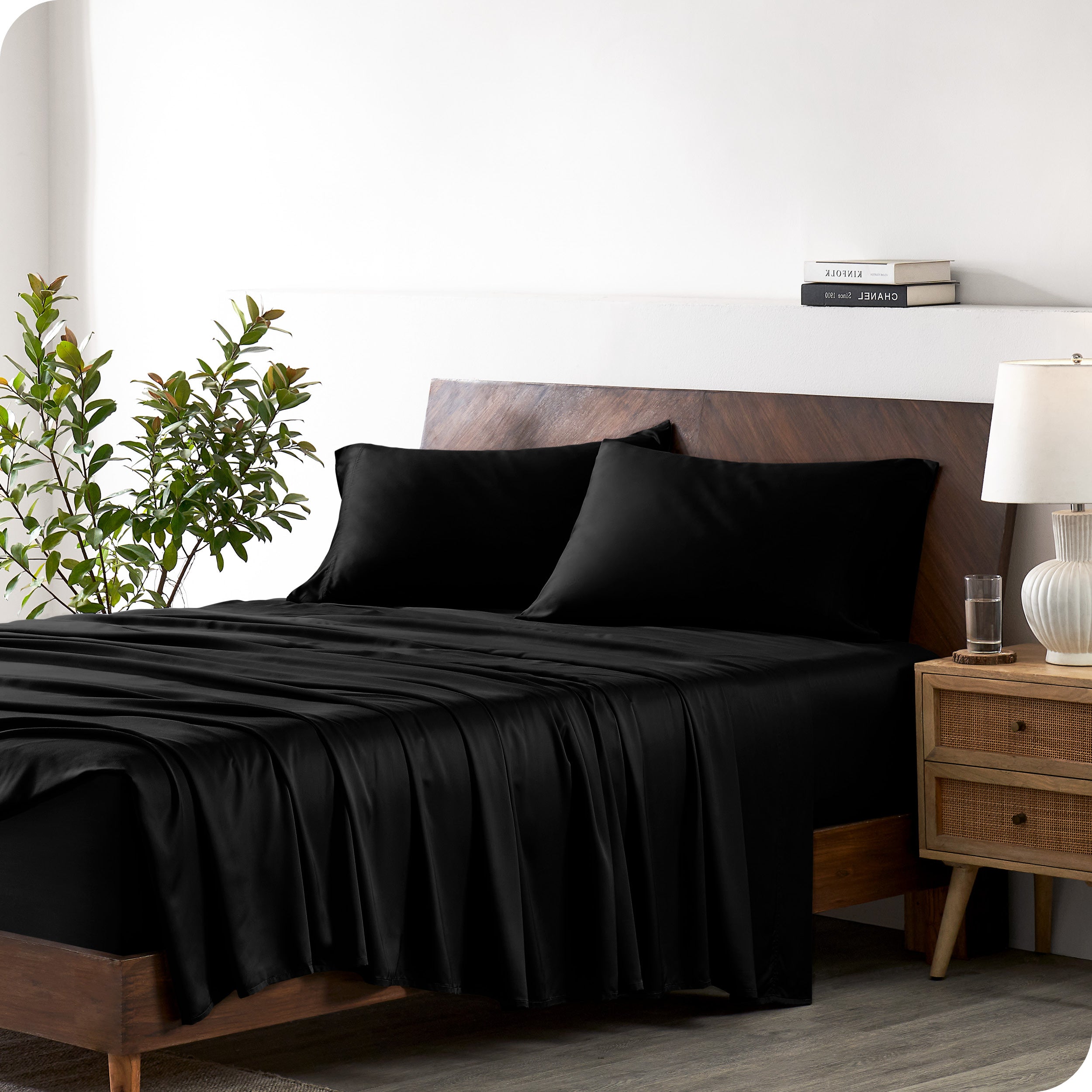 Modern bedroom with a bed against a white wall with a nightstand next to the bed. The bed has bamboo sheets draped over it.