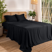 Bamboo sheets on a bed in a bedroom with plants and a window.