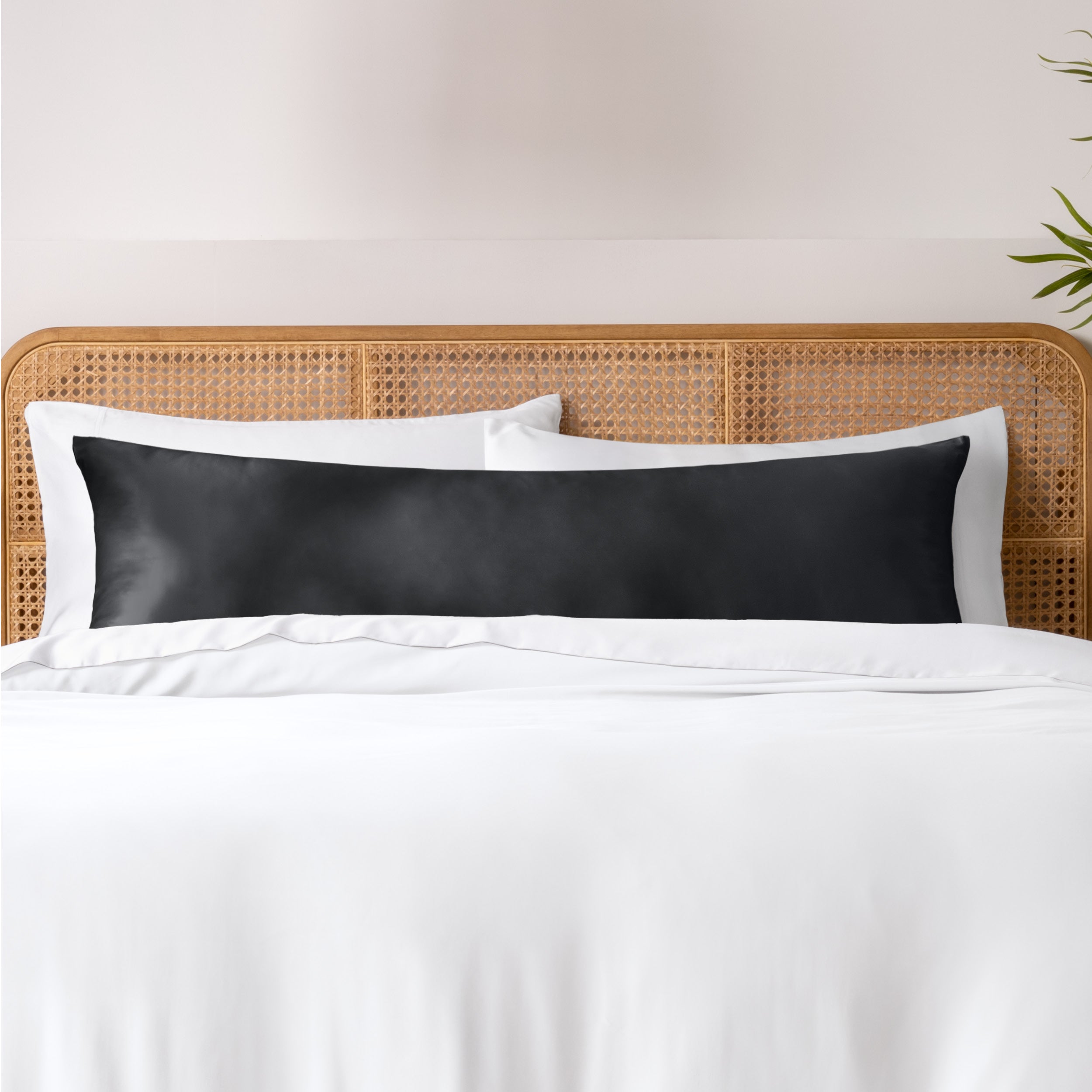 Bamboo body pillowcase on a bed with white bedding and a wicker headboard.