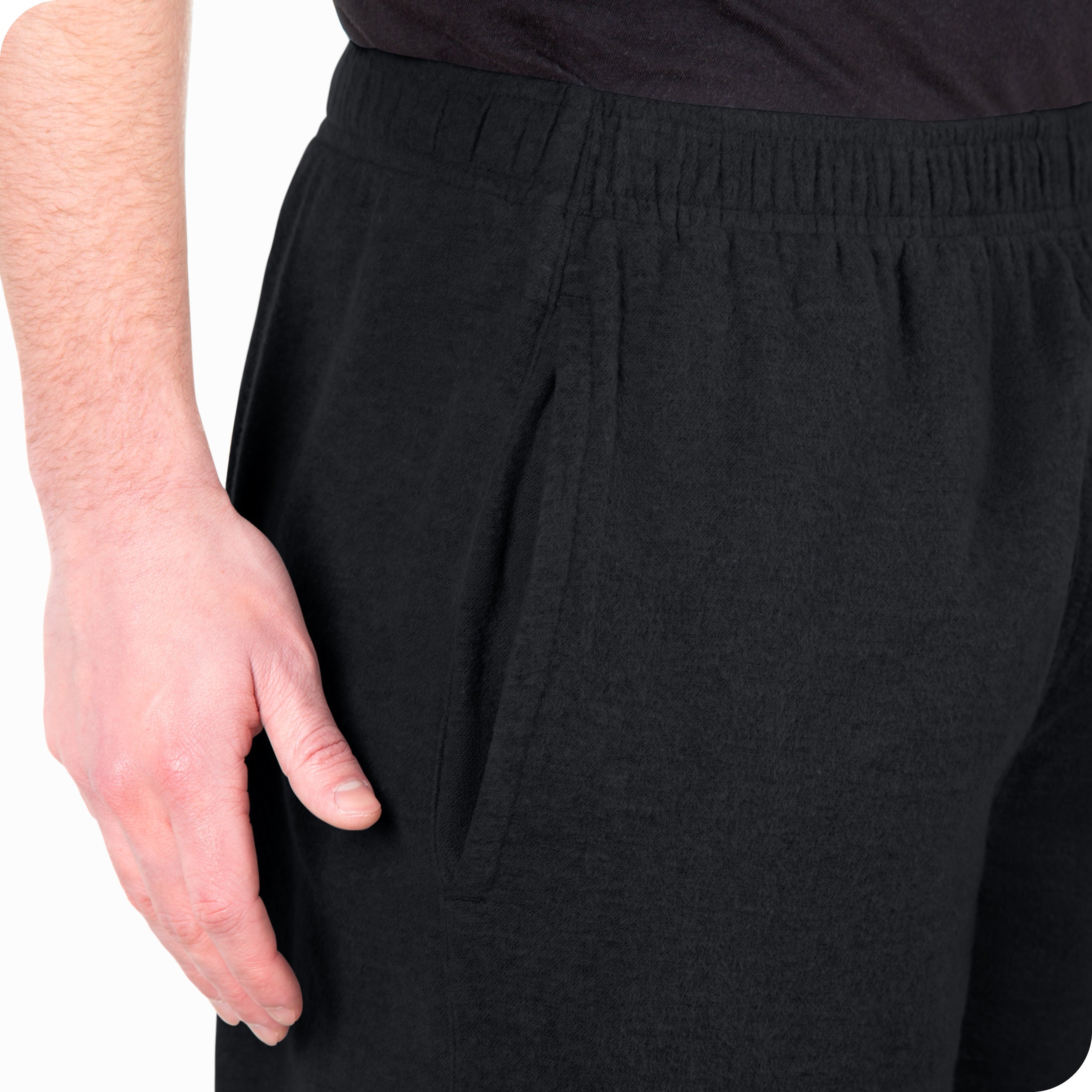 Close-up of a flannel pajama pocket with a man's hand nearby.