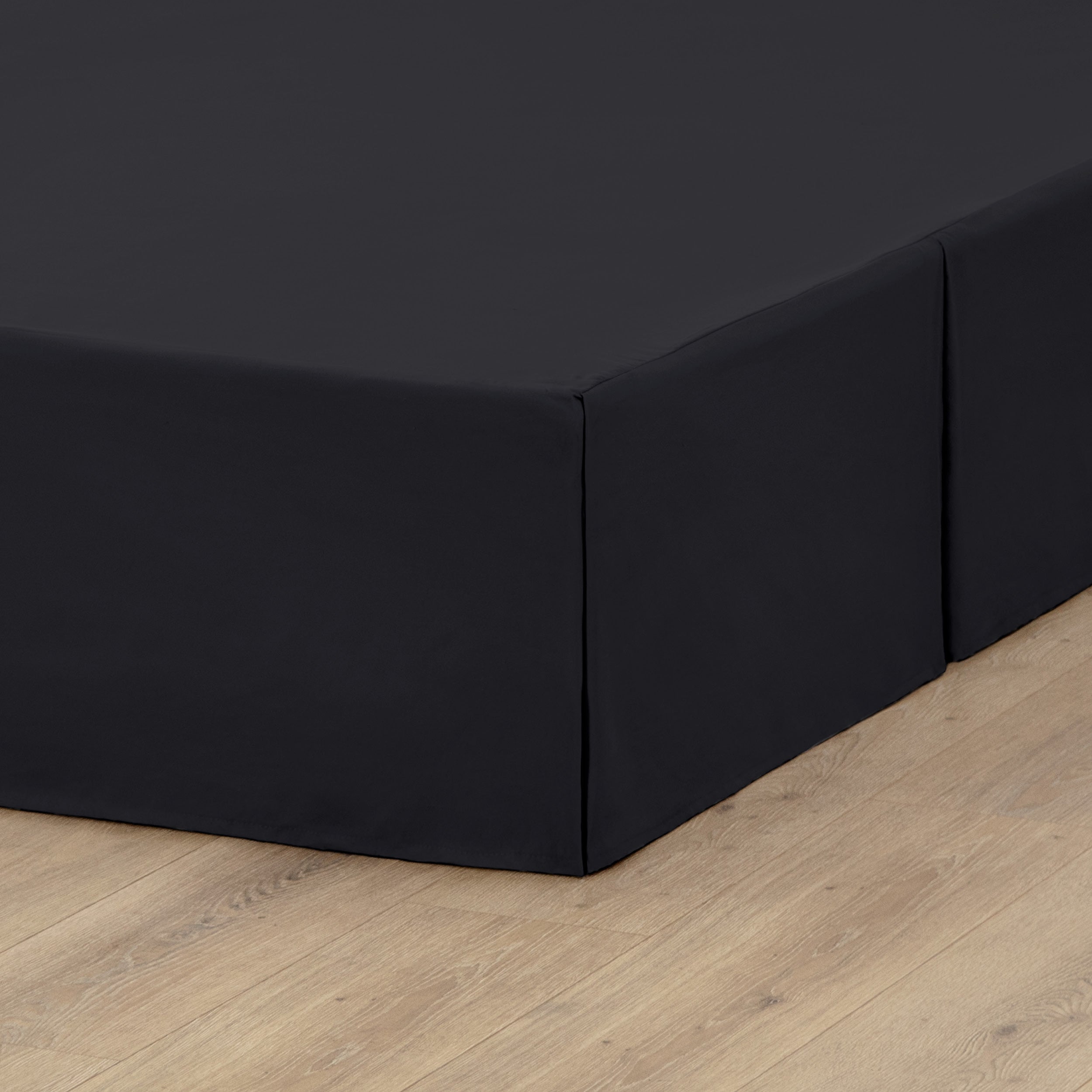 A box spring with a bed skirt on it