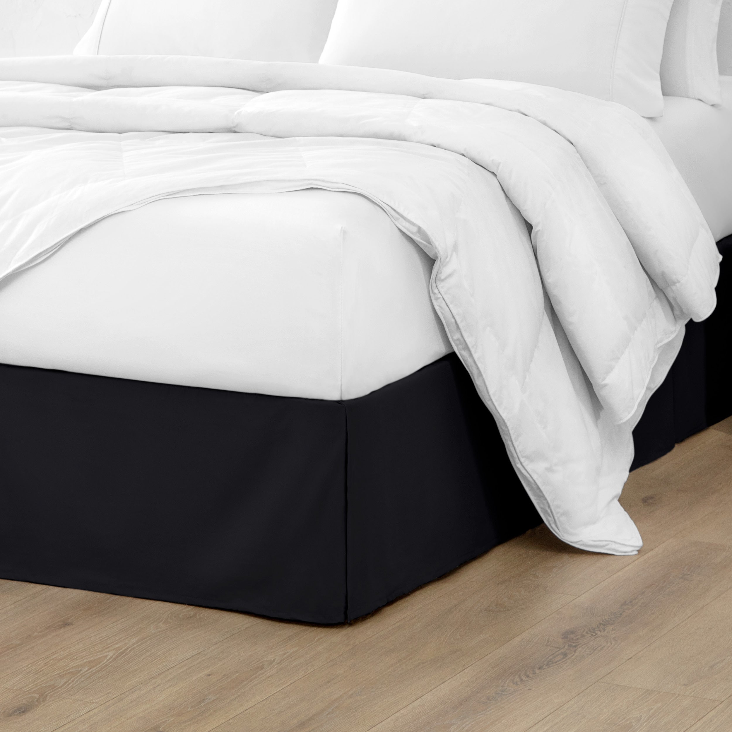 The corner of a bed with a bed skirt and comforter on it