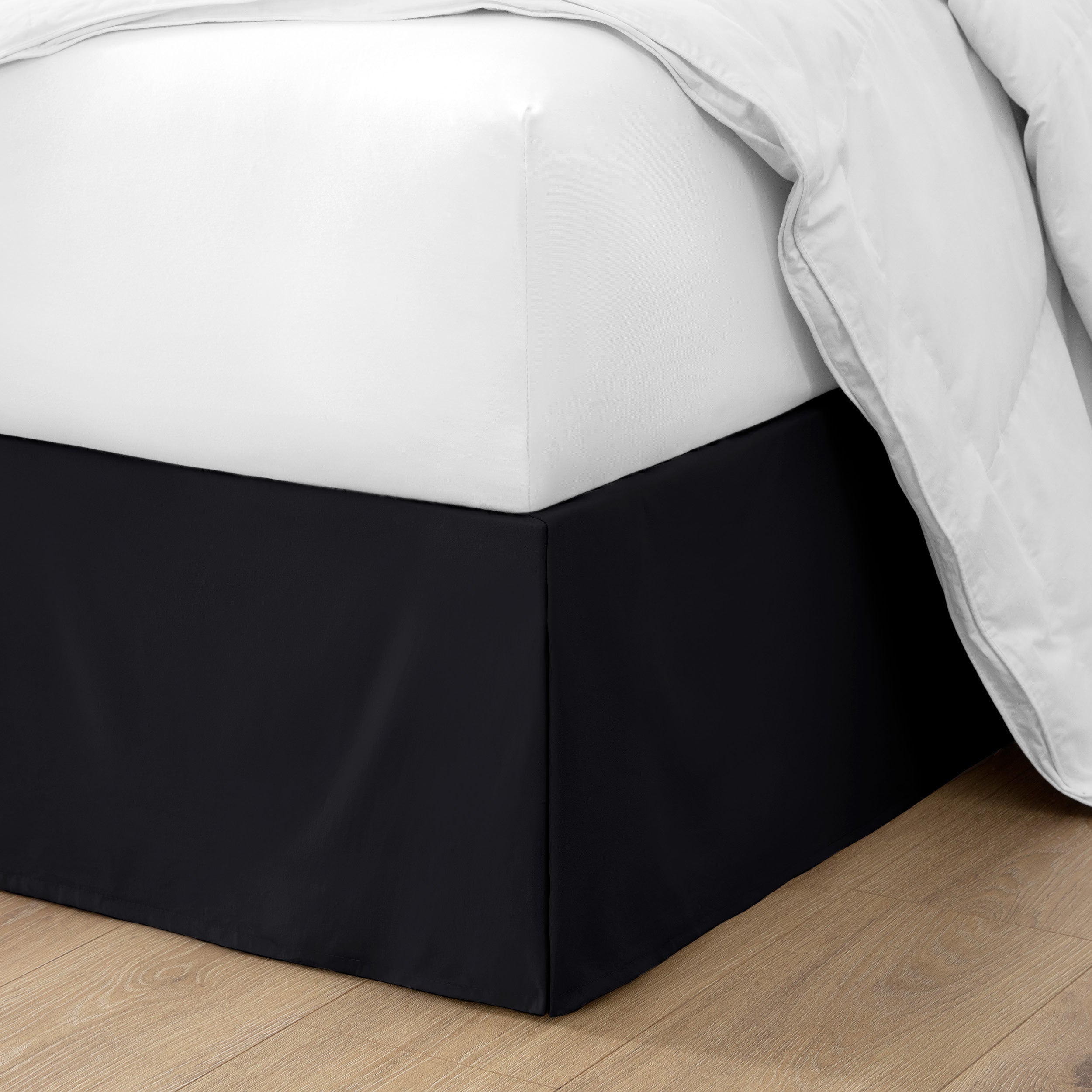 The corner of a bed with a bed skirt and comforter on it