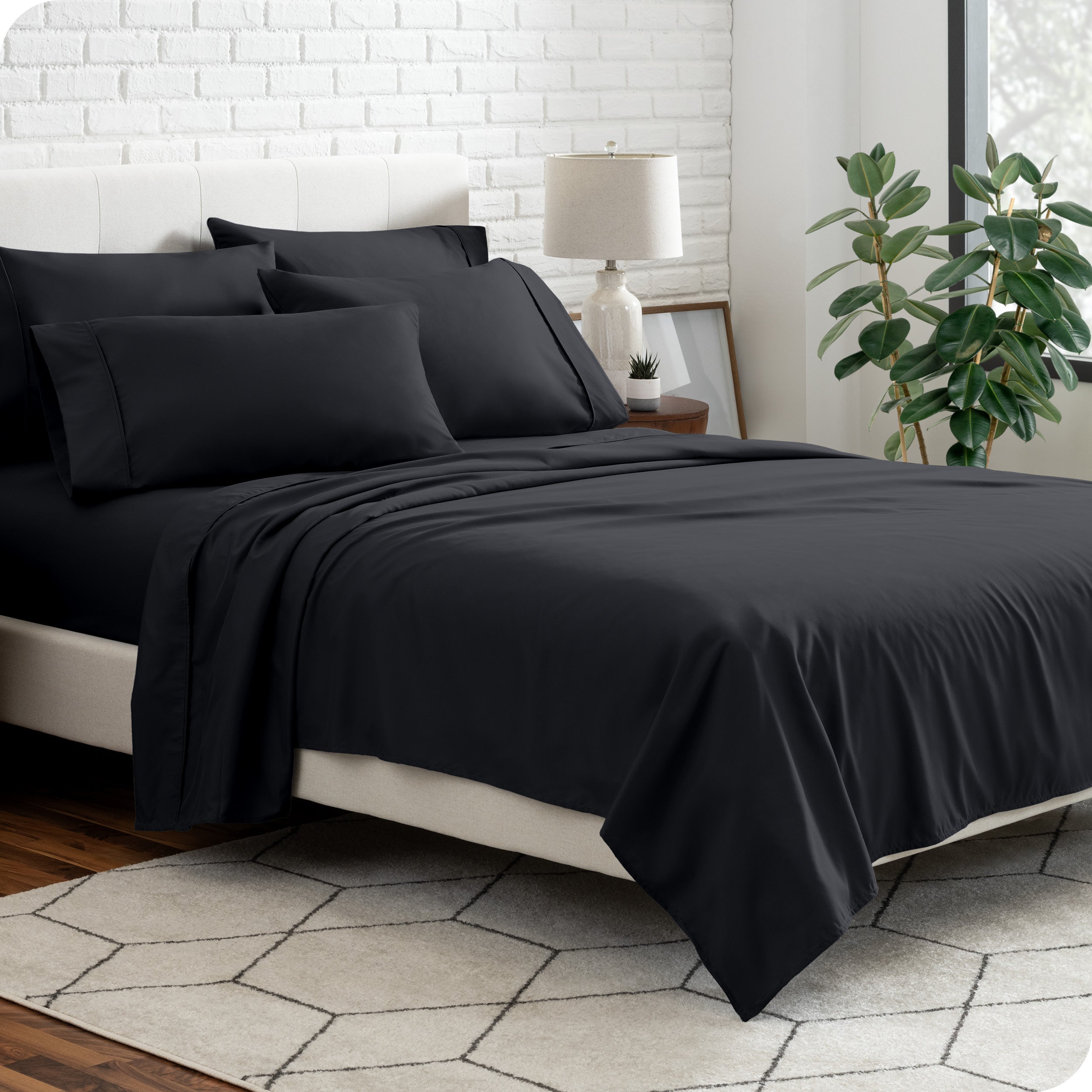 A bedroom setting with a bed made with the microfiber bed sheets and four pillows.