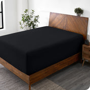 A wide corner view of a modern bed made with a microfiber fitted sheet on the mattress. 