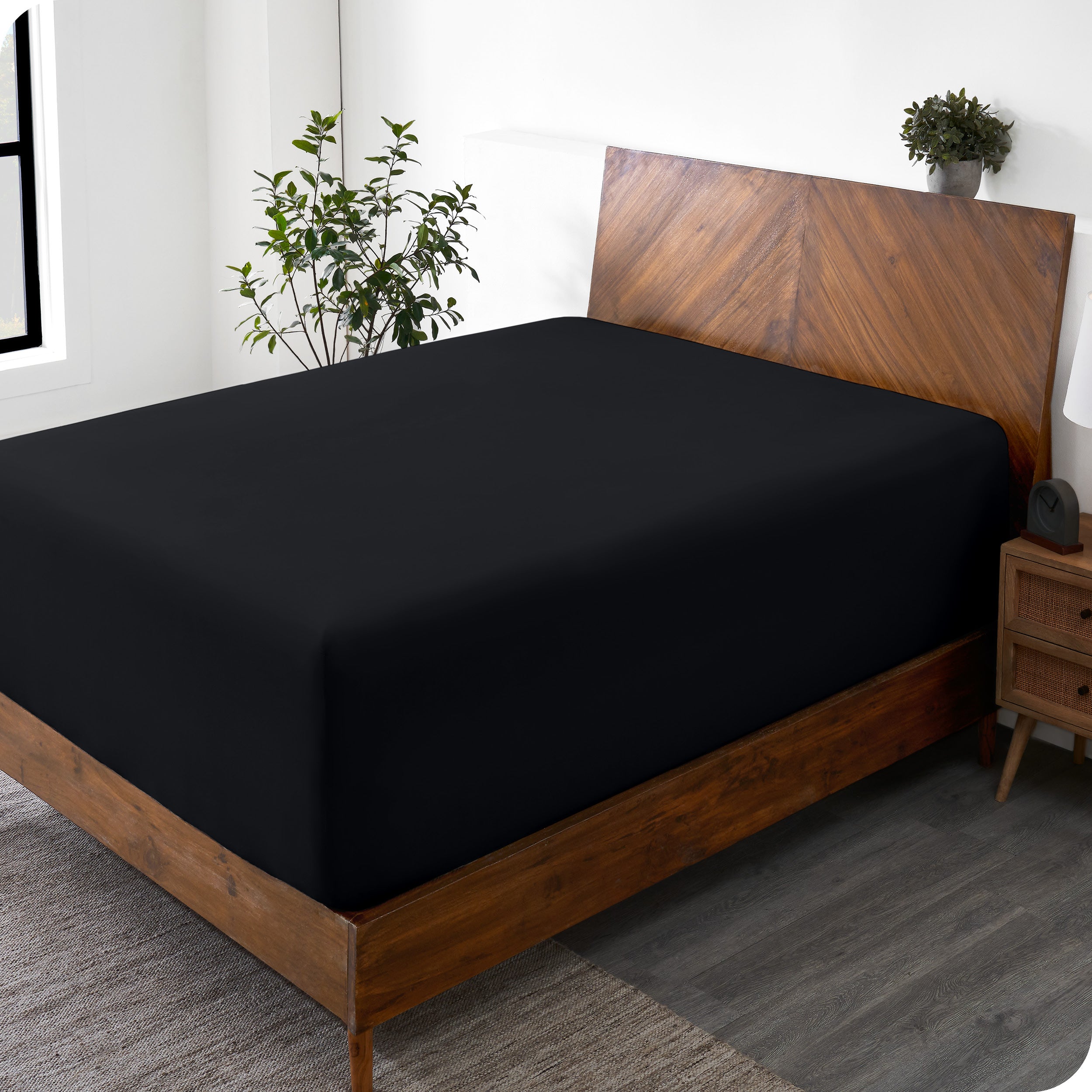 A wide corner view of a modern bed made with a microfiber fitted sheet on the mattress. 