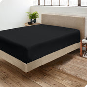 Corner view of a modern bed with a microfiber fitted sheet on the mattress. 