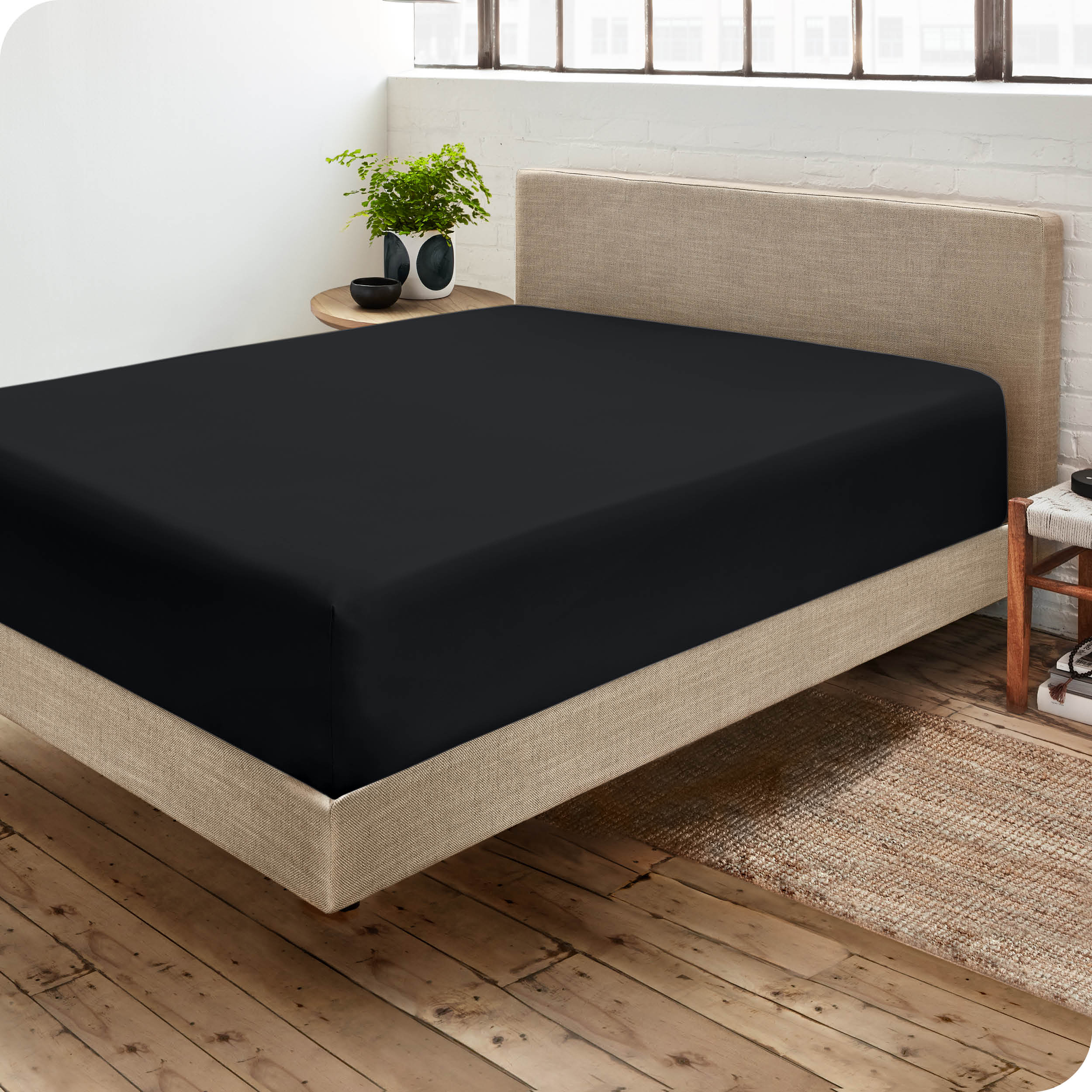 Corner view of a modern bed with a microfiber fitted sheet on the mattress. 