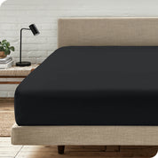 A bed with a microfiber fitted sheet on the mattress. 