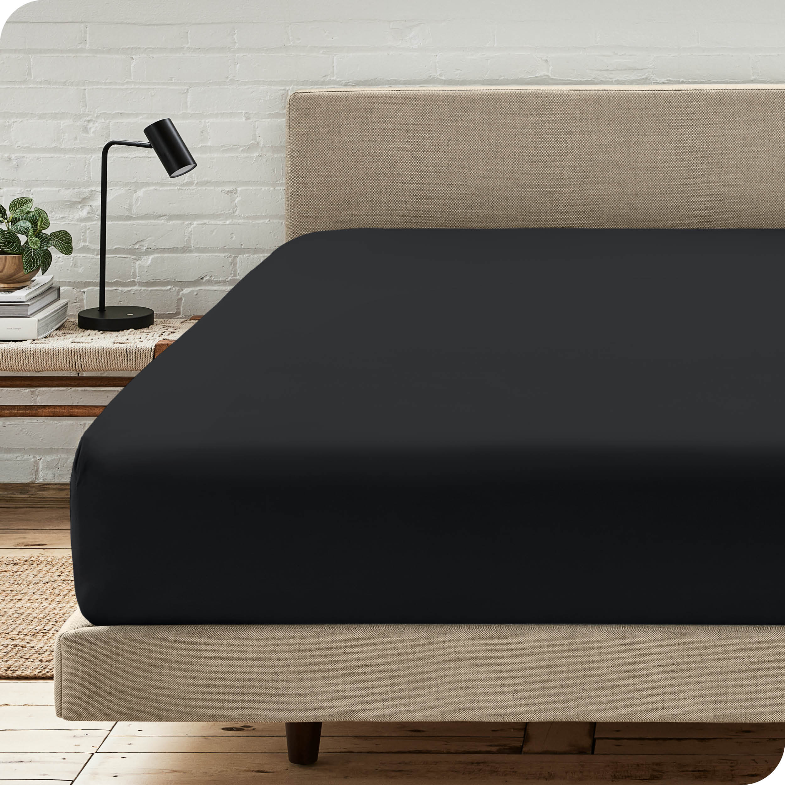 A bed with a microfiber fitted sheet on the mattress. 