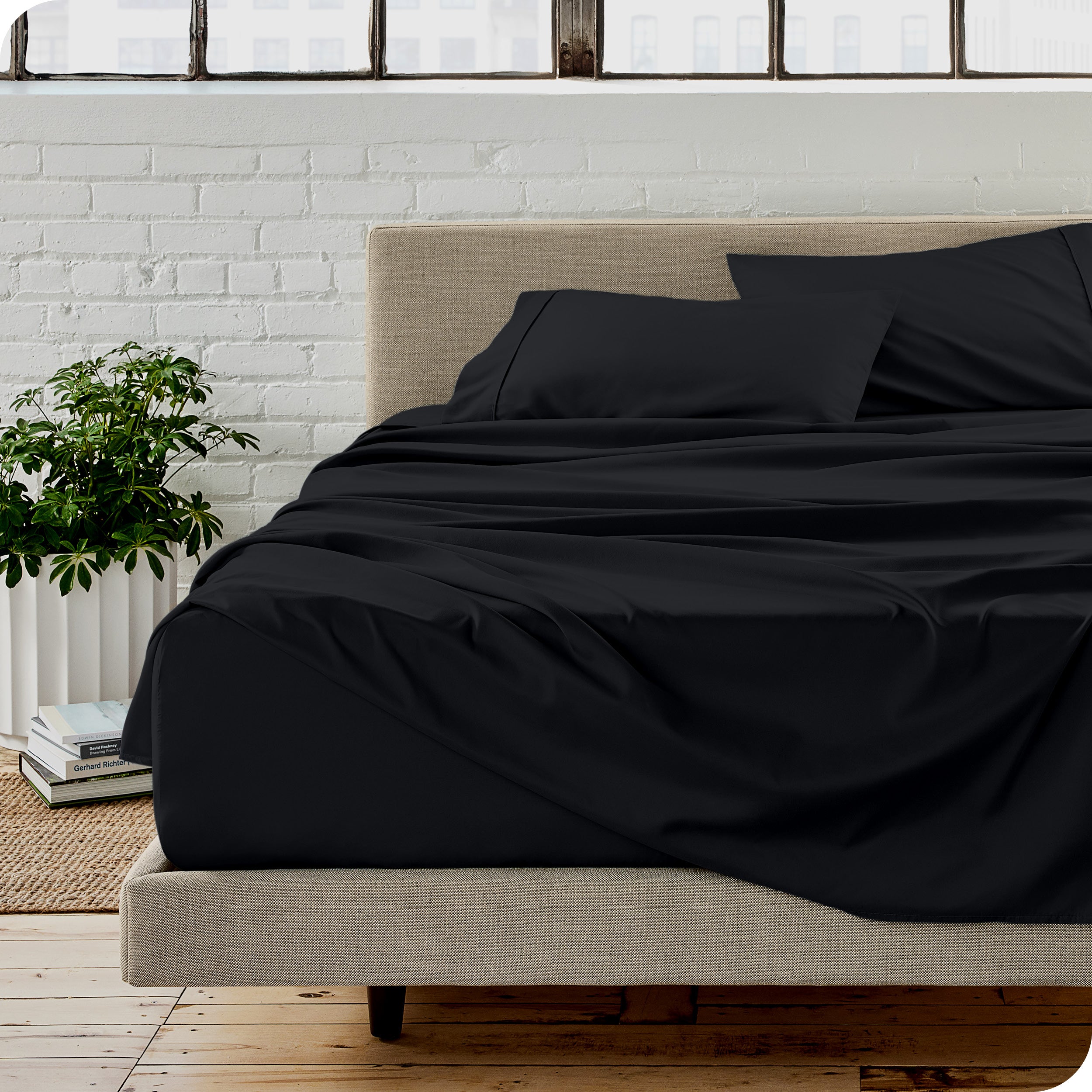 Microfiber sheets on a bed with a brick wall behind it