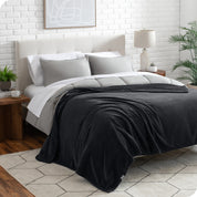 A textured microplush blanket is draped over a bed made with grey duvet set