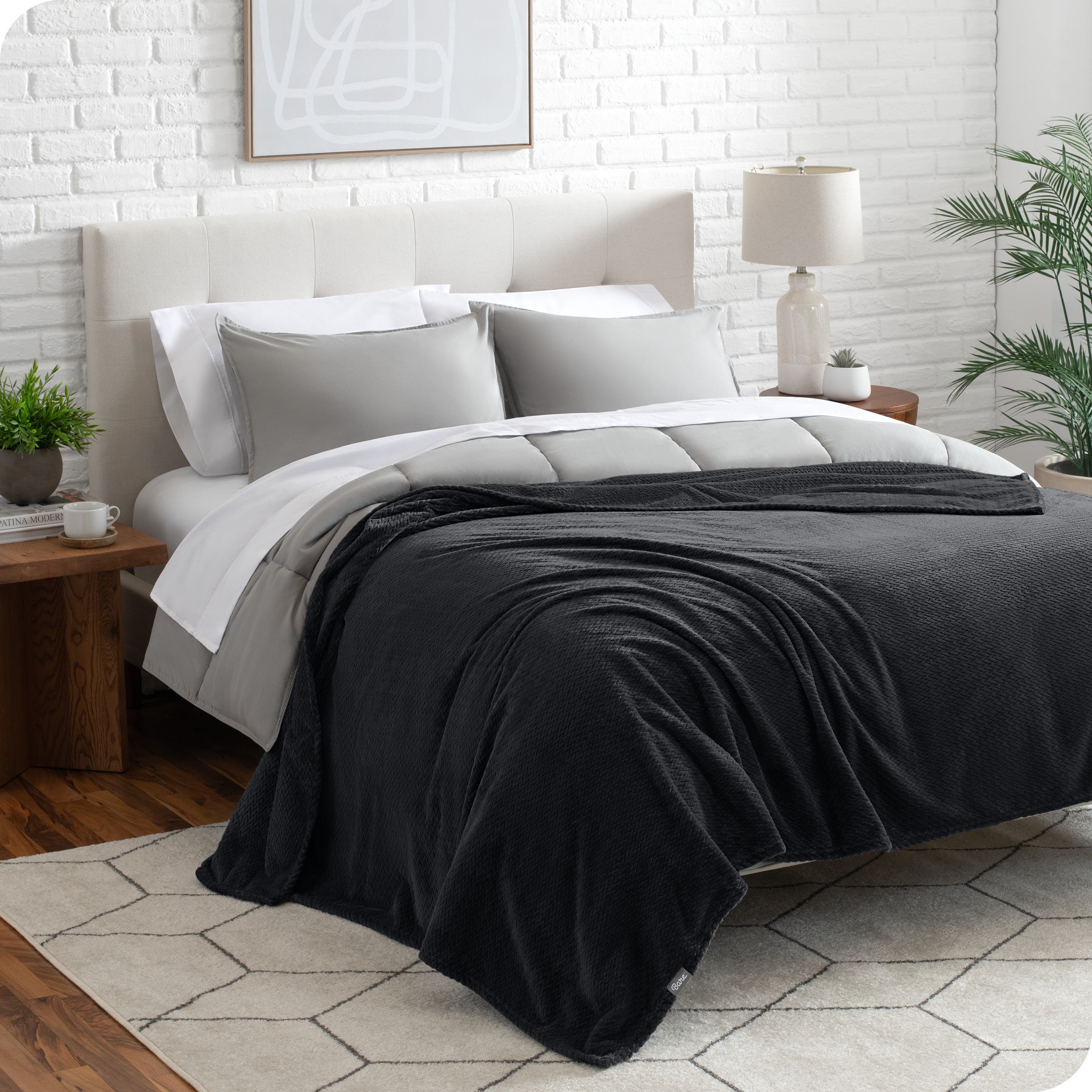 A textured microplush blanket is draped over a bed made with grey duvet set