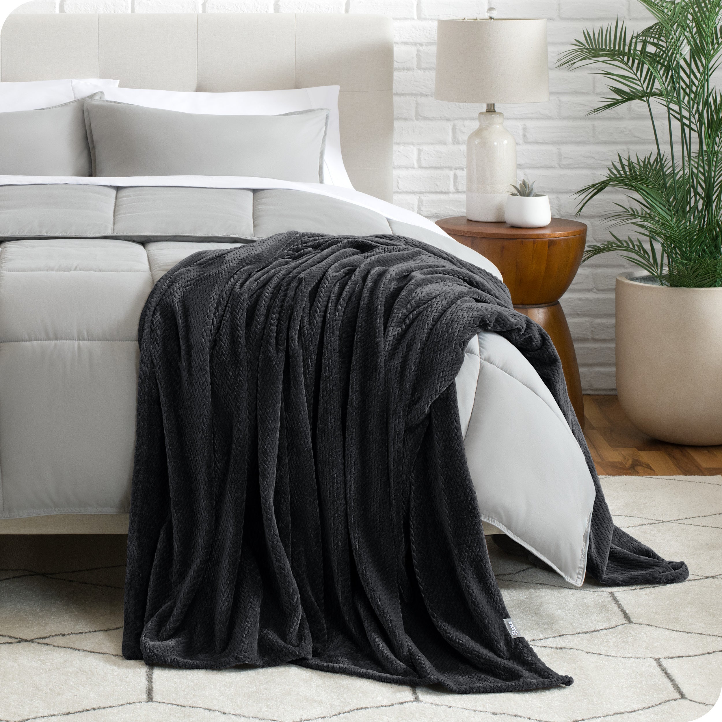 A textured microplush blanket is hanging over the corner of a bed