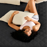 A women is laying on the bed with quilted mattress pad from above.