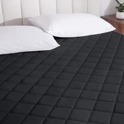 A mattress pad on a bed with two pillows from above.
