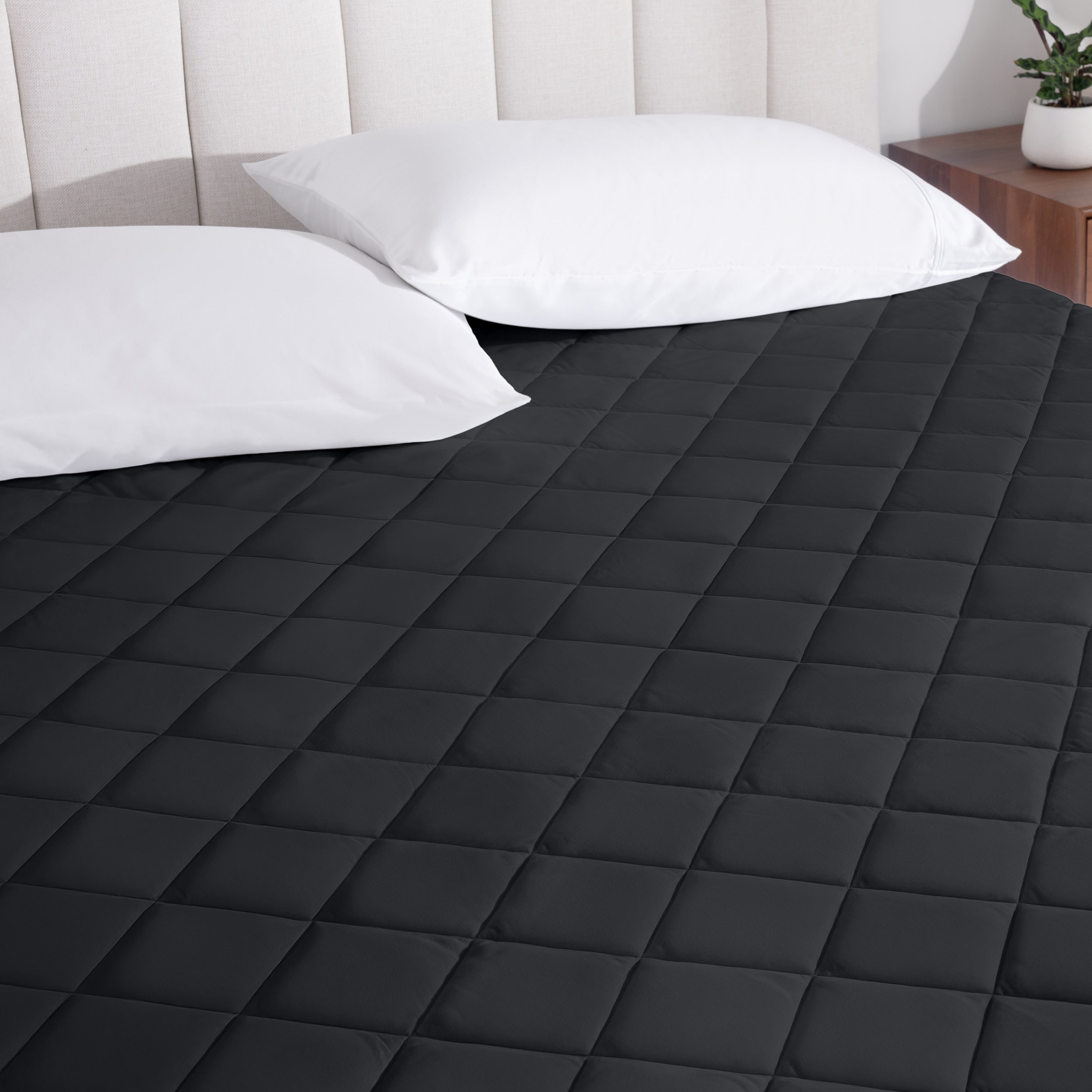 A mattress pad on a bed with two pillows from above.