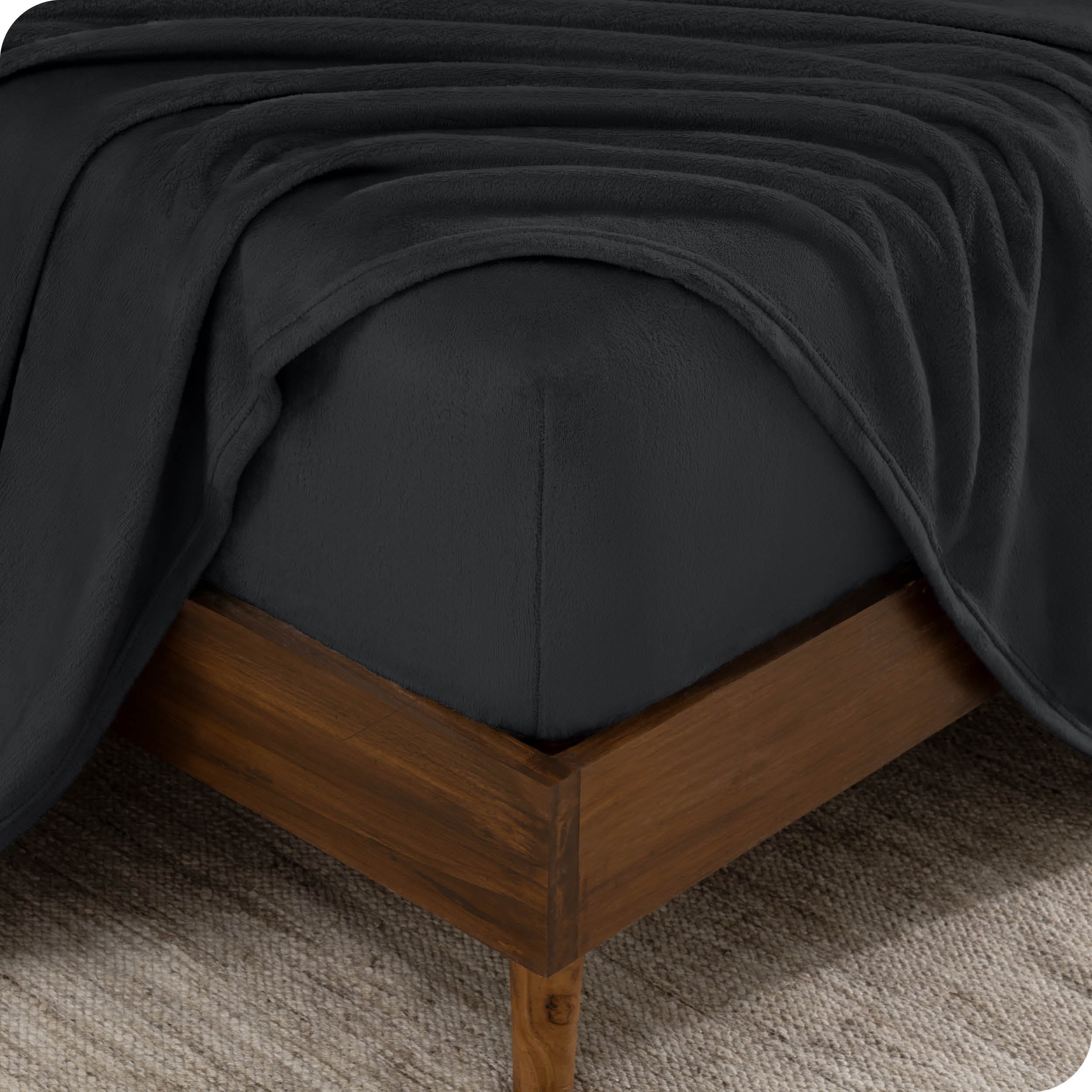 A corner of a mattress with a fitted sheet and a flat sheet on it.