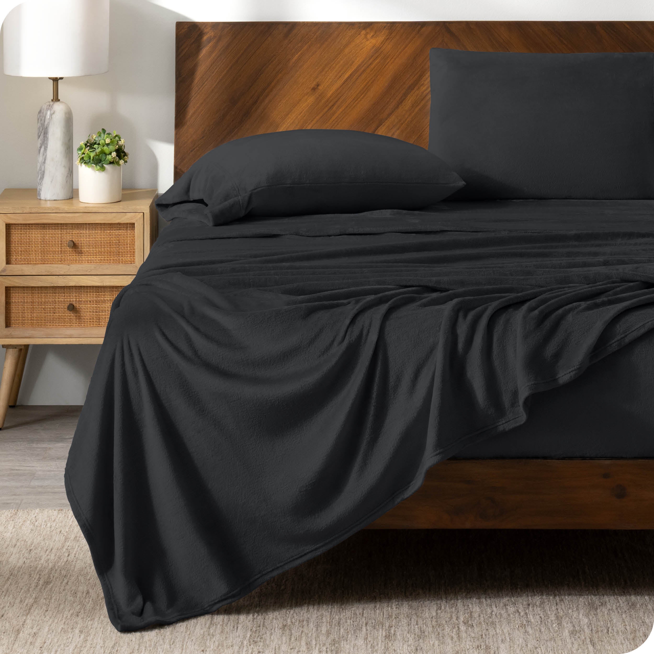 A black sheet set on a bed with a wooden bed frame