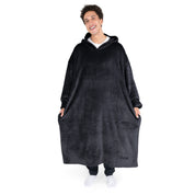 An adult is standing while wearing a long microplush wearable blanket