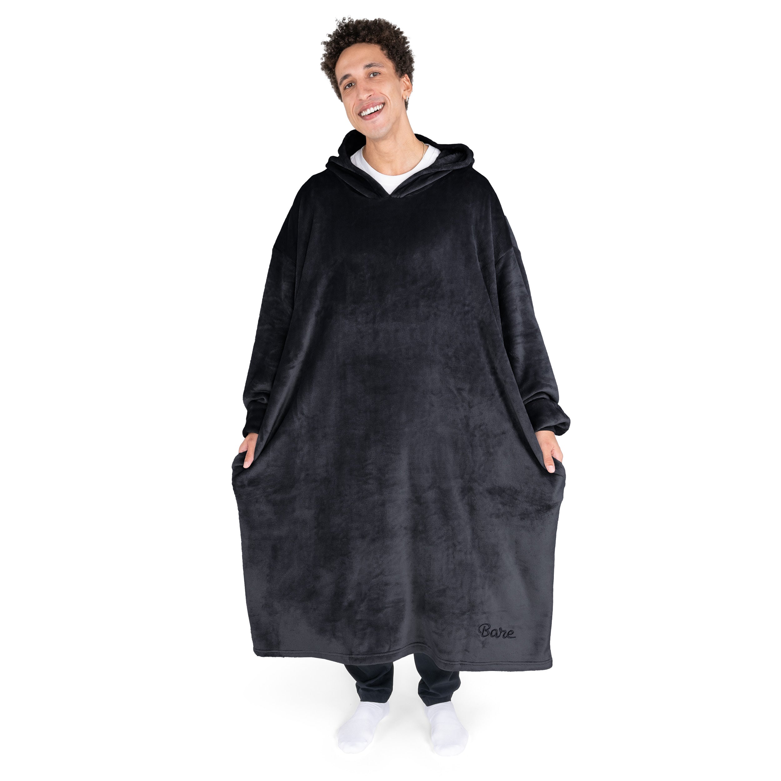An adult is standing while wearing a long microplush wearable blanket