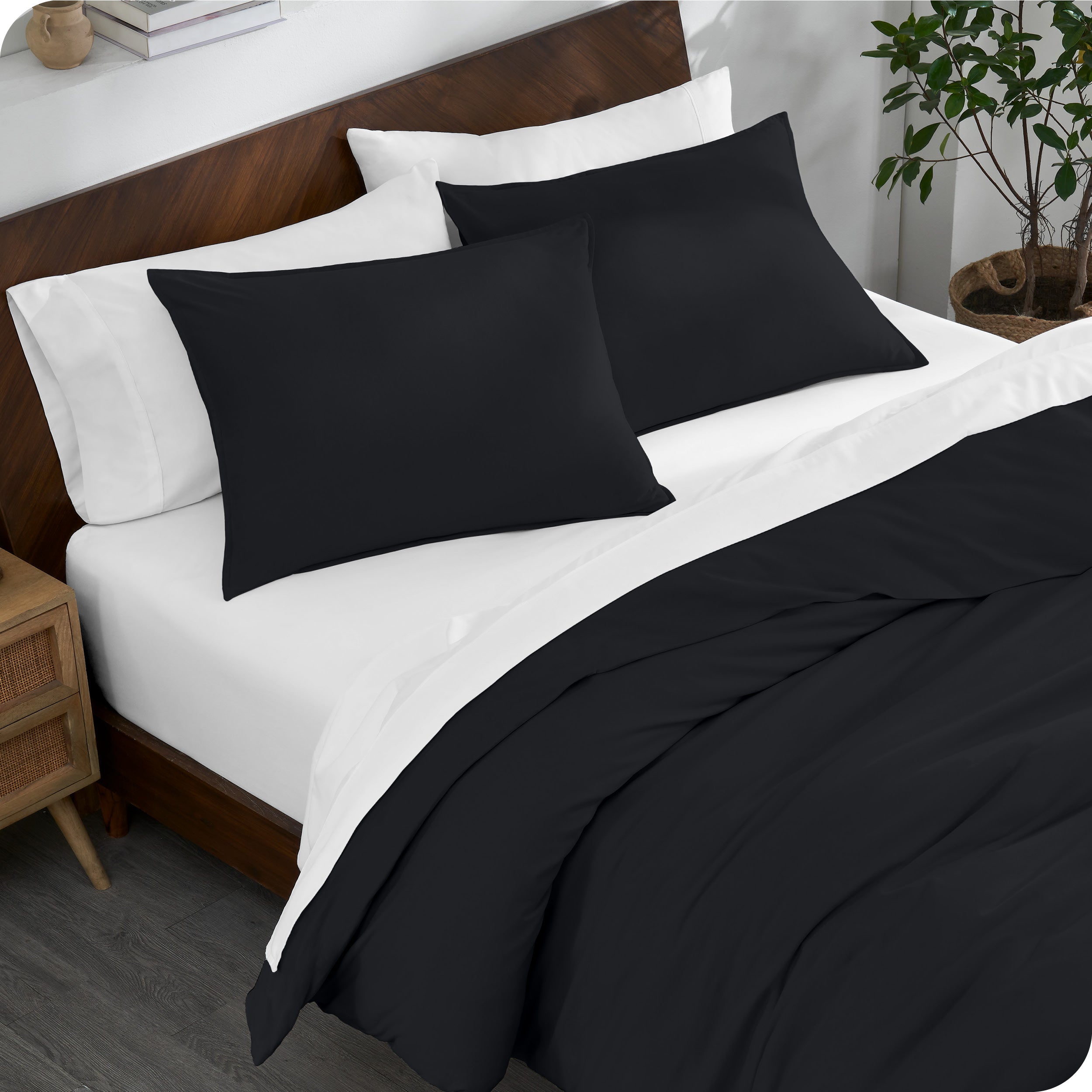 A bed made with an organic jersey duvet cover, pillow sham covered pillows and extra pillows